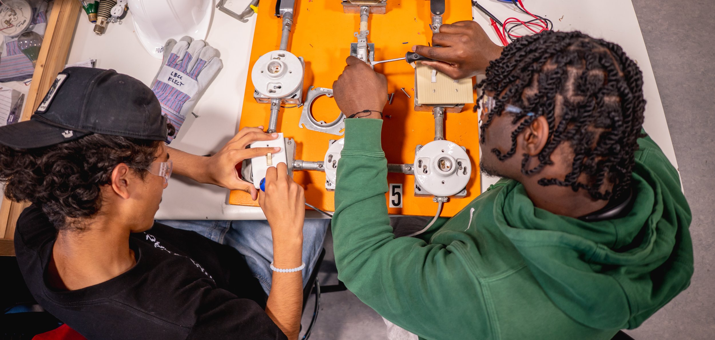 Two apprentices working on electrical switches