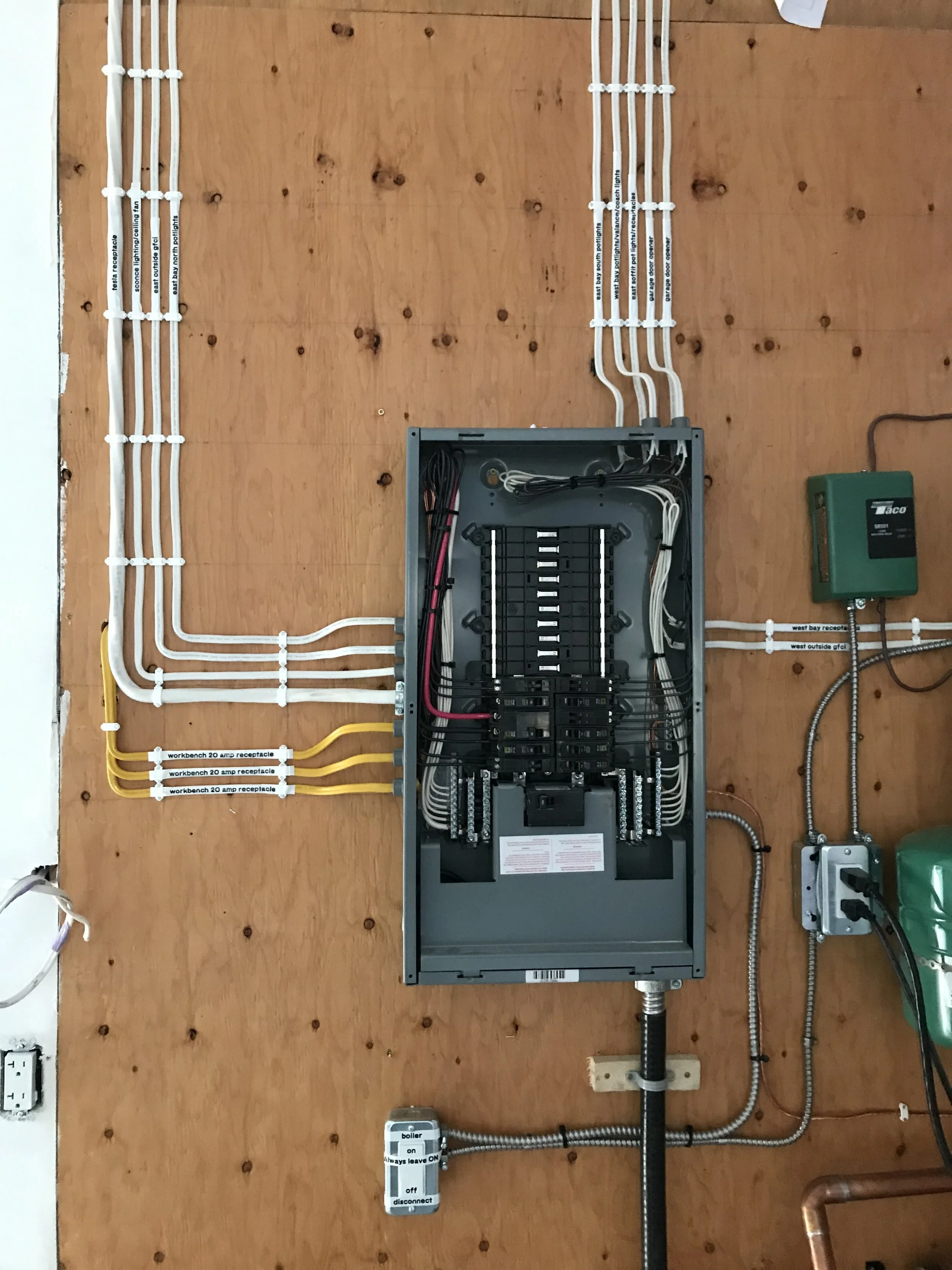 Electrical job by Clearwater Electrical. Electrical wiring and panel on a wooden wall, with labels on wires, a green device, and a boiler disconnect switch.