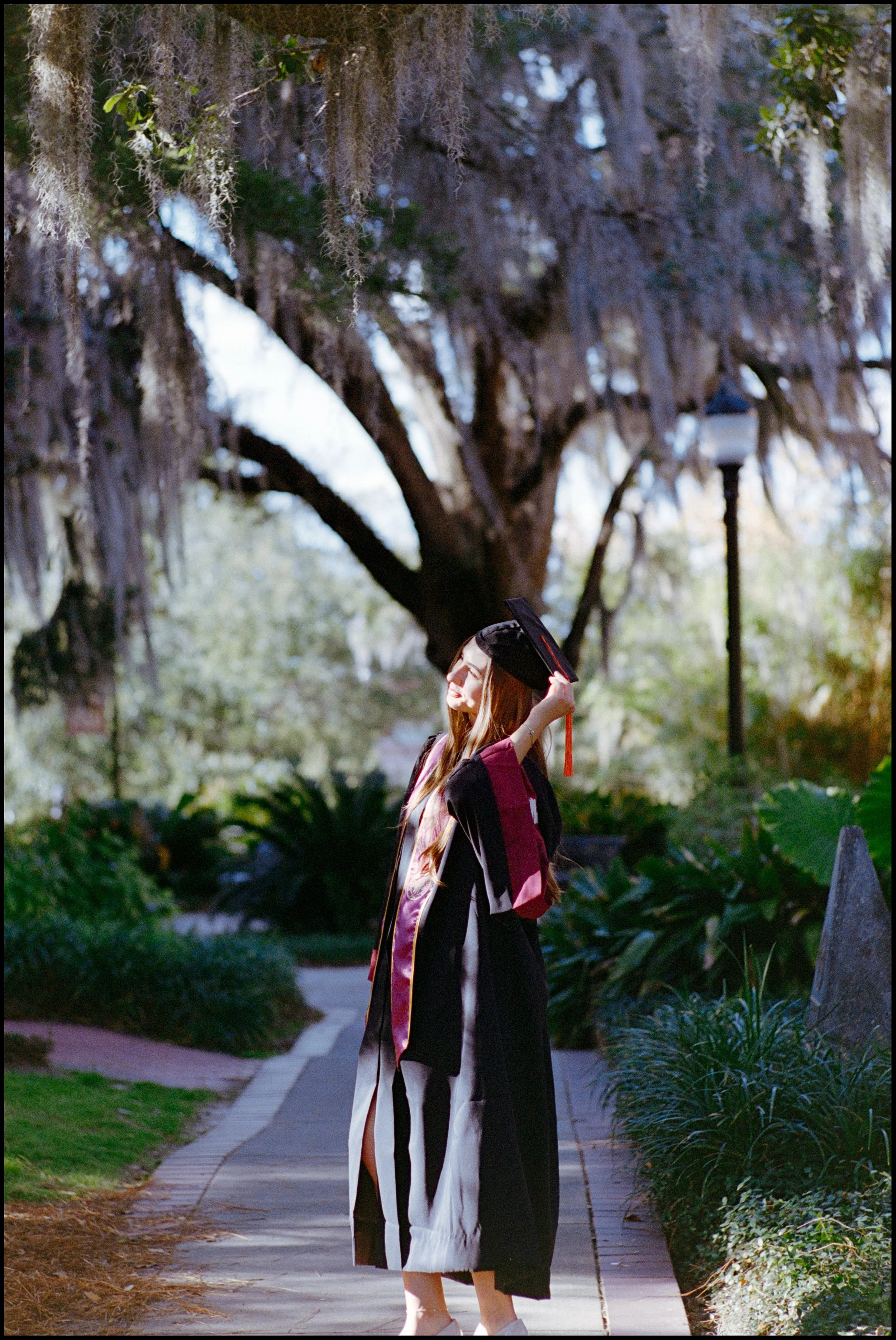 Graduation cap and gown on a graduate standing outdoors on a sidewalk