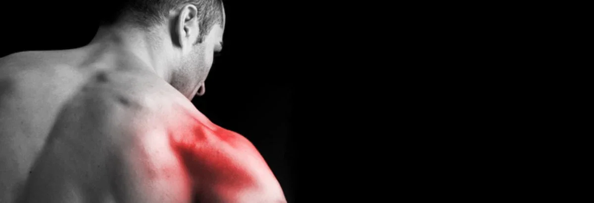 A man with a red, inflamed shoulder, viewed from the side against a black background.