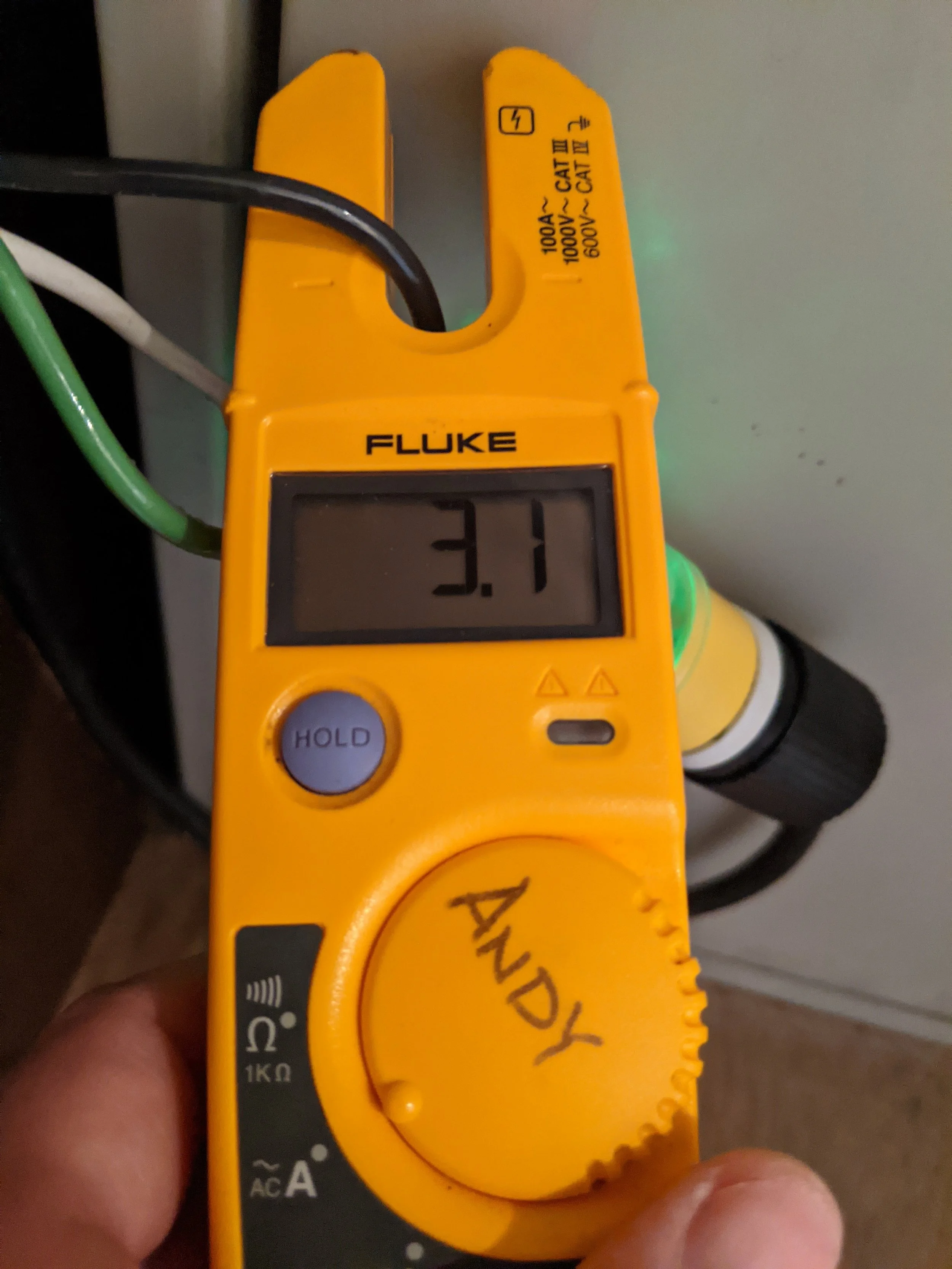 Digital multimeter showing a reading of 3.1 volts, with green, white, and black wires connected to it, labeled with handwritten
