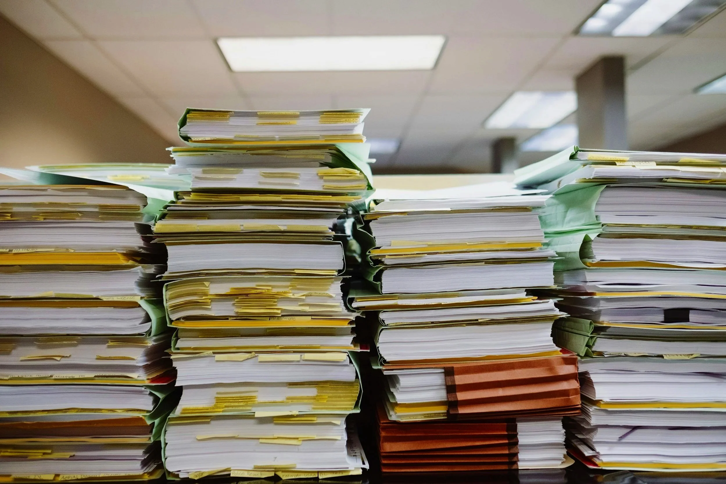 Stacks of organized papers and files on a desk in an office setting