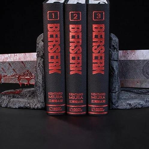 Three books titled "BERSERK" by Kentaro Miura standing upright between carved stone sculptures against a black background.
