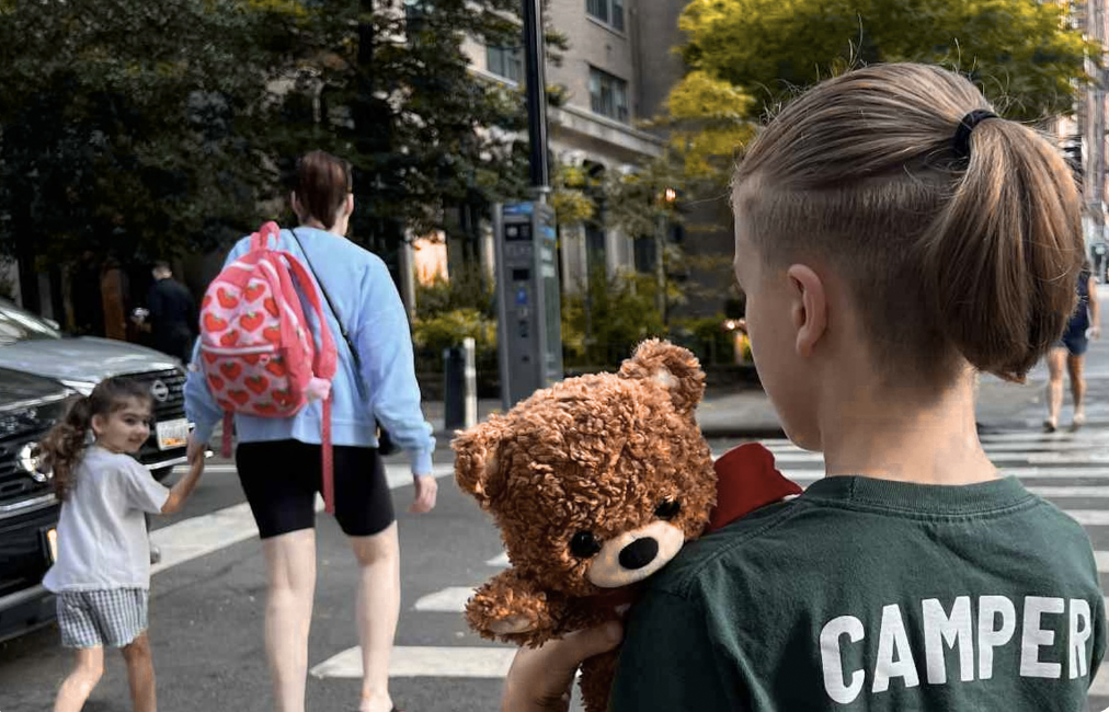 Boy holding teddy bear in street