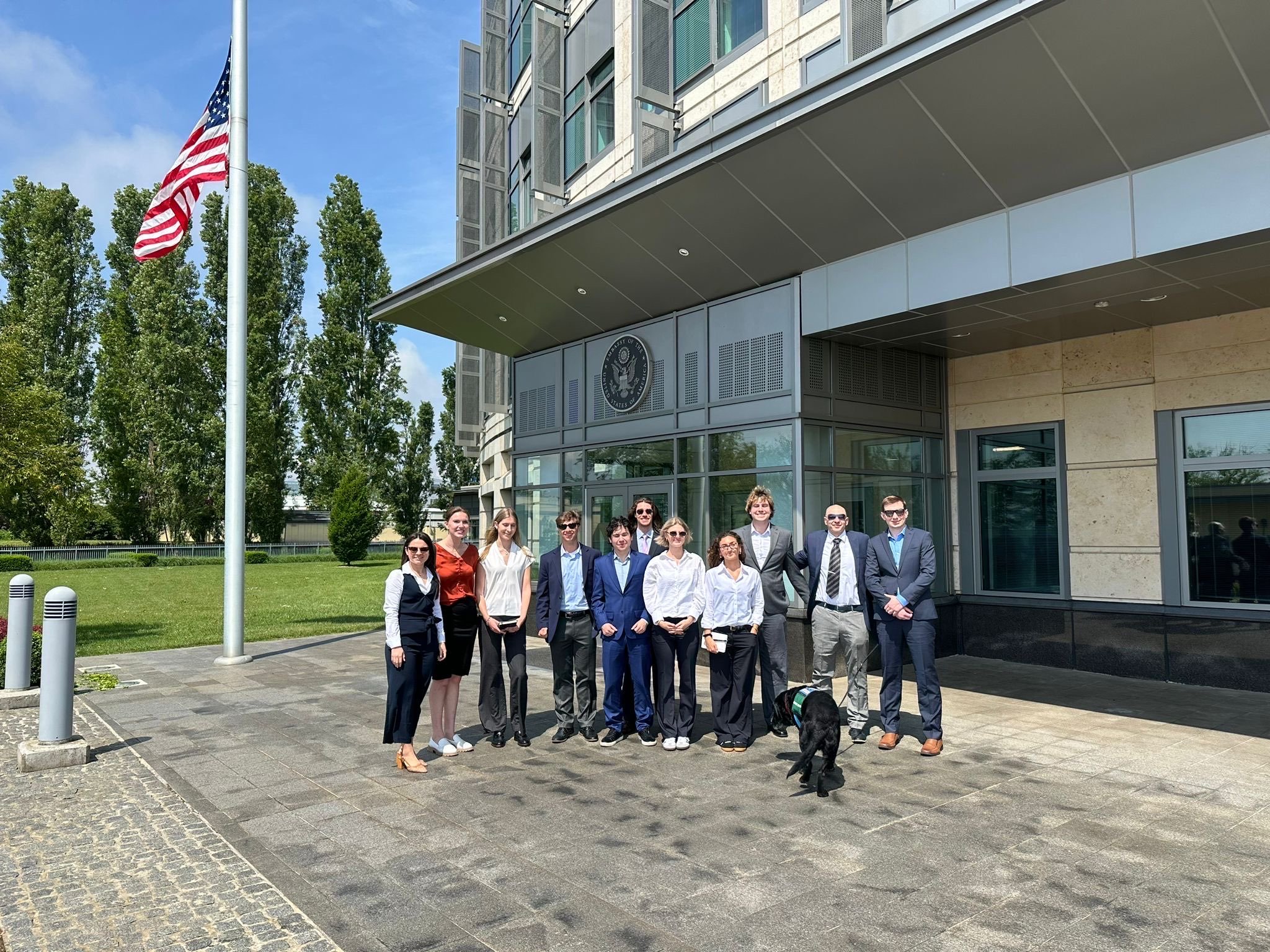 Group of people standing outside a government building with an American flag and the United States seal.