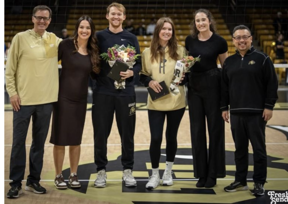 Group of six people standing on a basketball court, some holding bouquets and awards, celebrating an achievement.