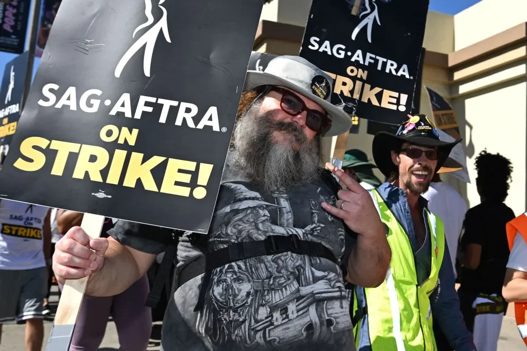 People protesting with signs that read "SAG-AFTRA ON STRIKE" outside a building.