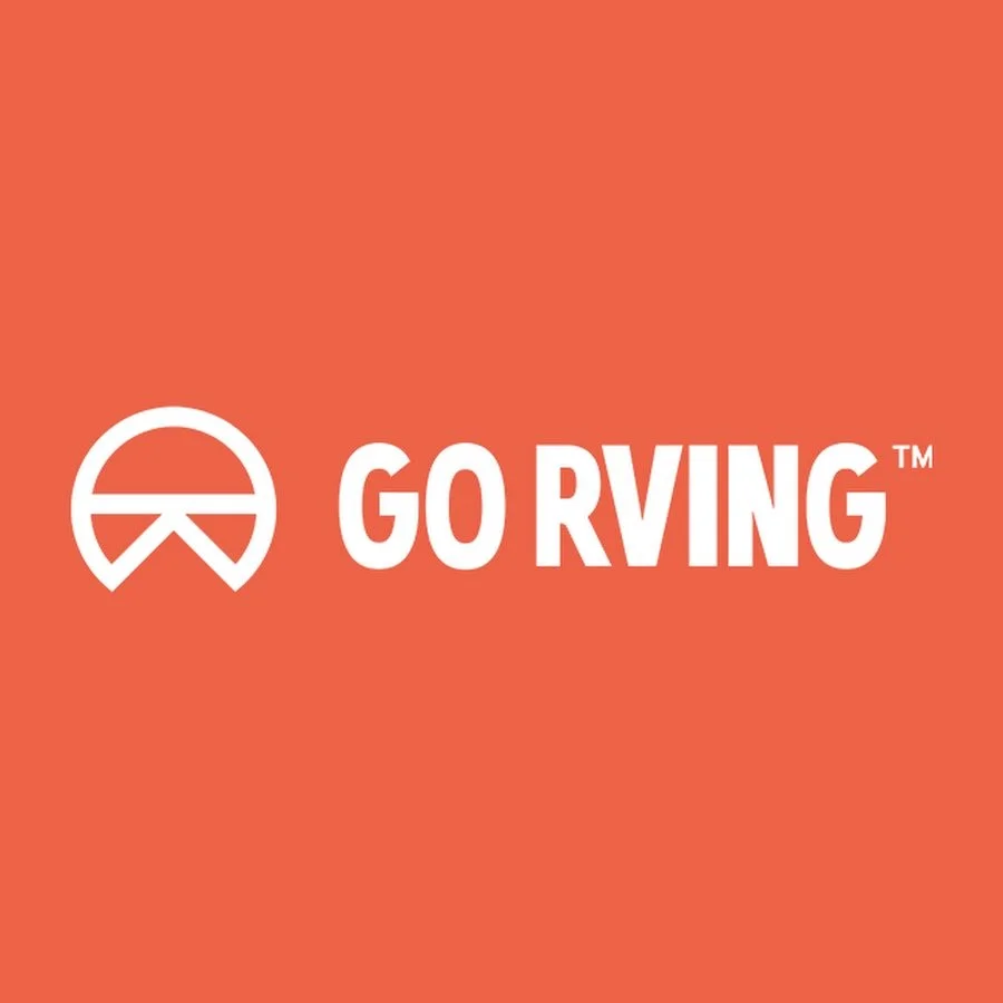 A logo with a circular design and a cross inside it, next to the text "GO RIVING™" in bold white letters on an orange background.