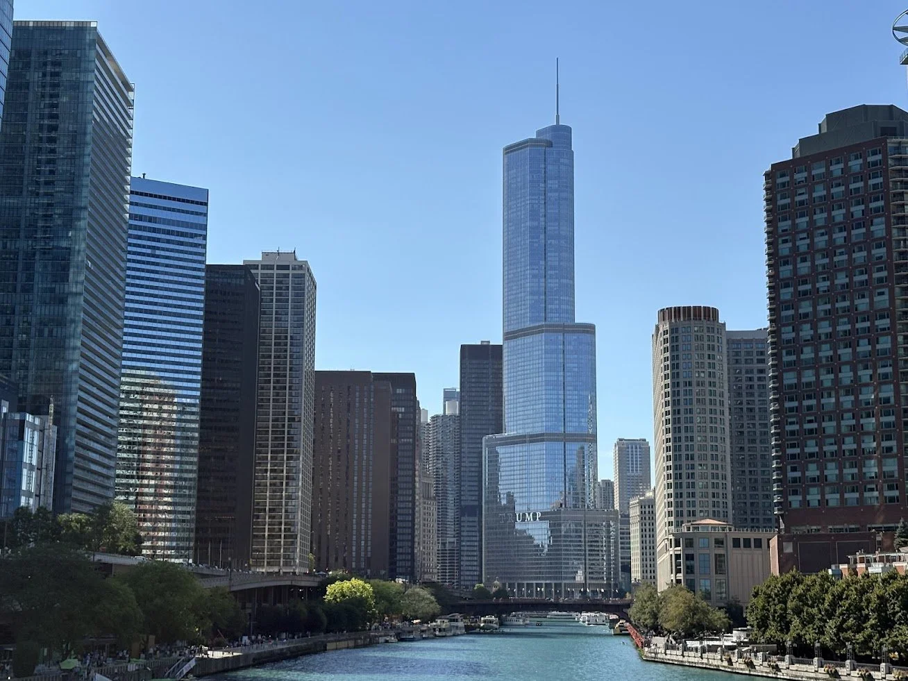 Chicago skyline with tall modern buildings along a river under a clear blue sky.