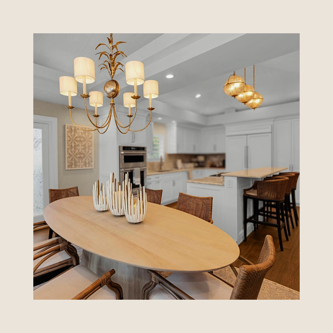 A modern kitchen and dining area with a wooden oval table, six chairs, a chandelier, pendant lights, and decorative candles.