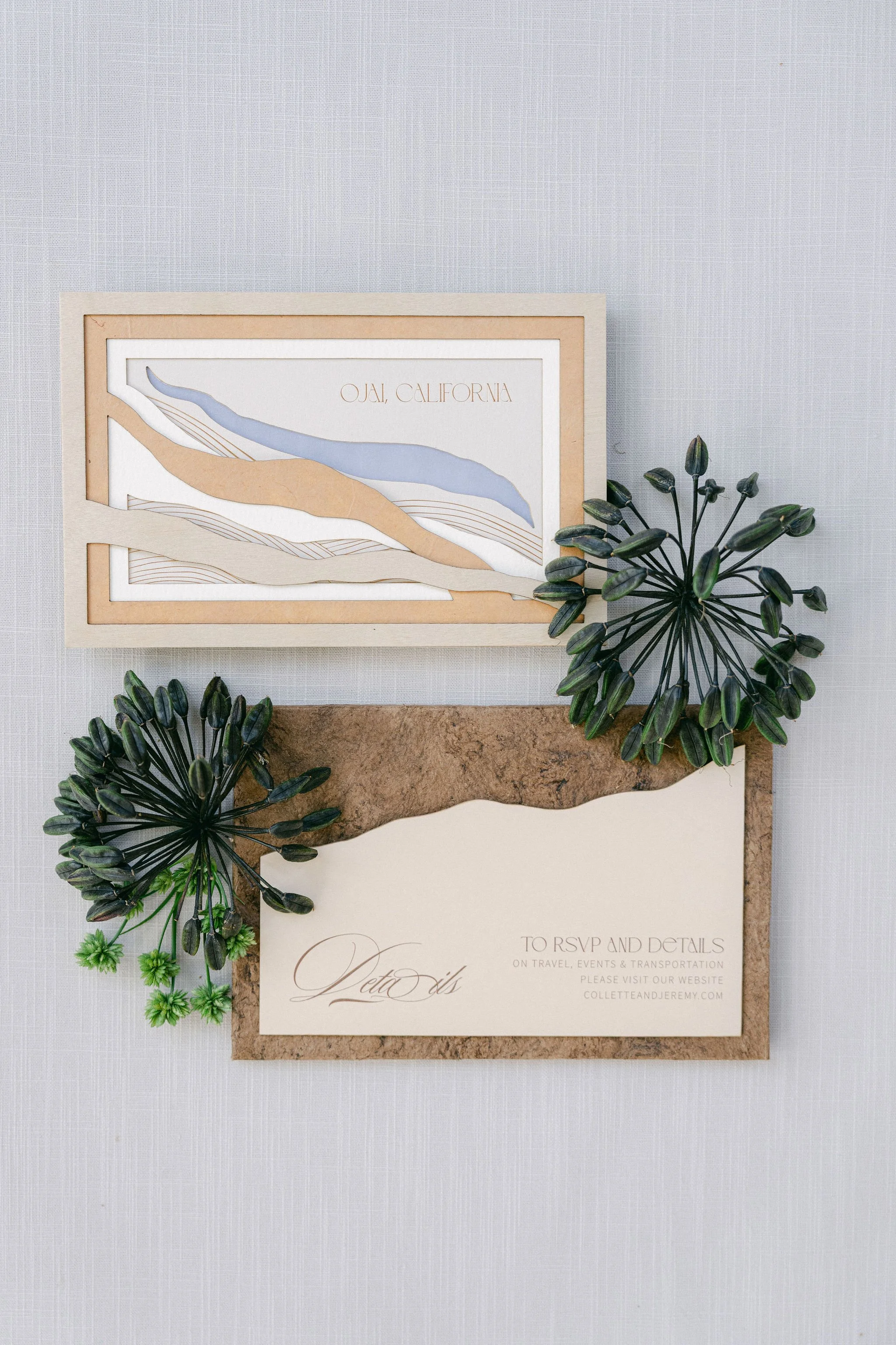 Wedding invitation with a topographical map of Ojai, California, decorated with green plants on a light textured background.