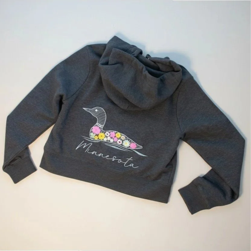 Dark gray cropped sweatshirt with MN state bird, the loon, embroidered on the back with beautiful flowers on the loon's body and the word "Minnesota" stitched underneath. 