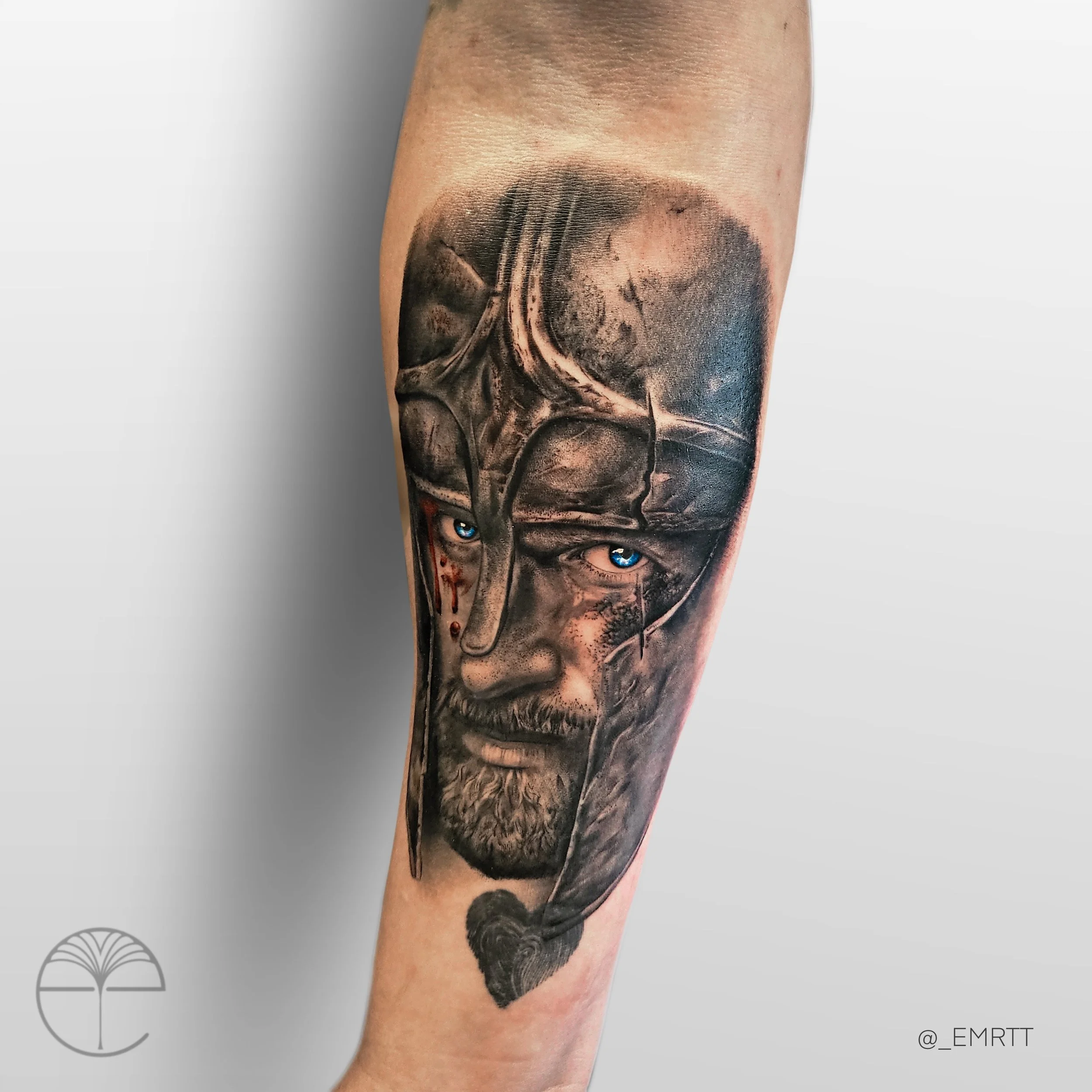 Tattoo of a warrior with a beard, blue eyes, and a helmet, with a moon and a starry sky in the background, on a person's arm.