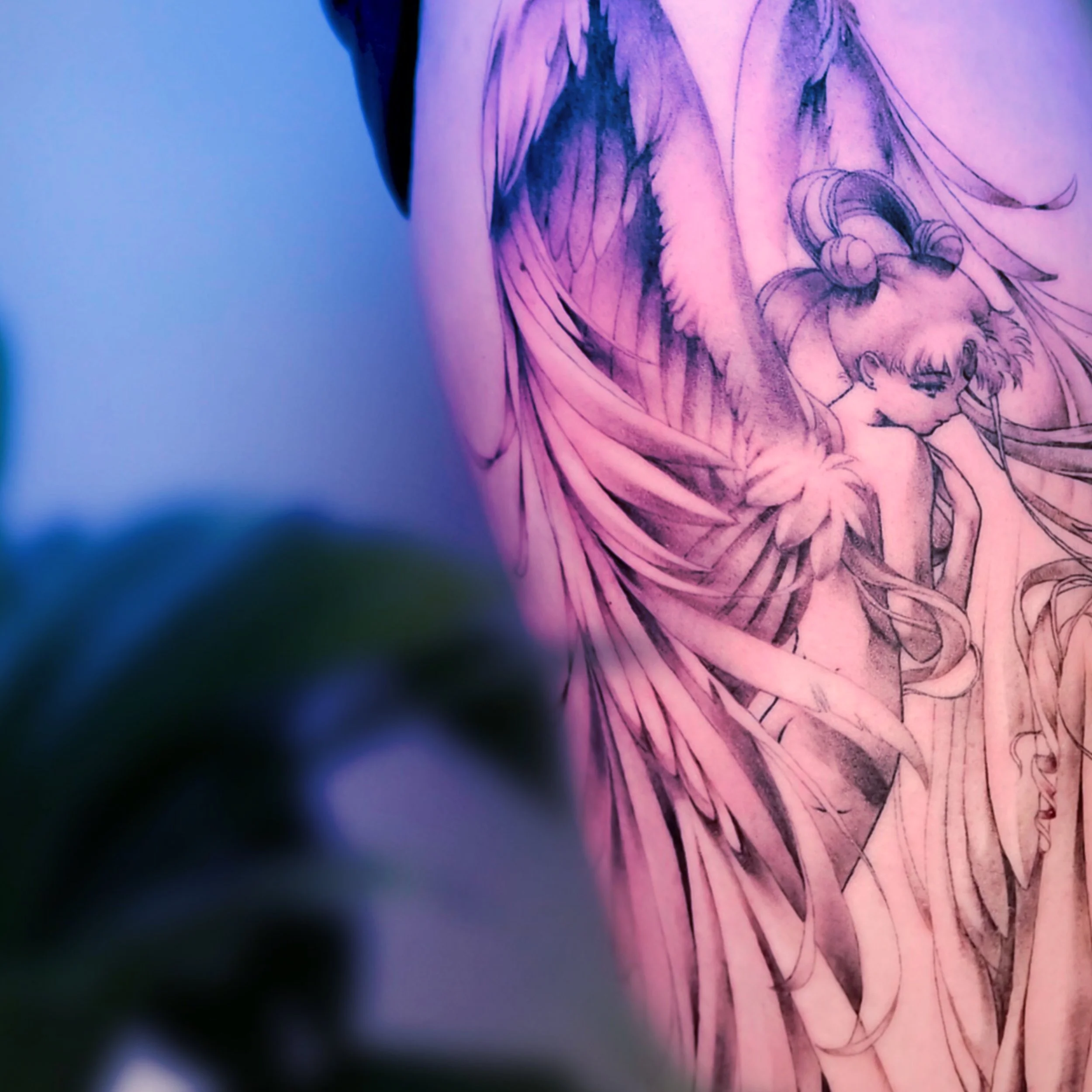 A detailed black and gray tattoo of a female character with long flowing hair and angel wings on a person's side torso.