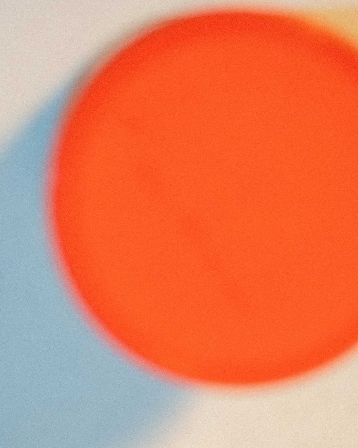 Close-up of a blurred orange circular object with blue and beige background.