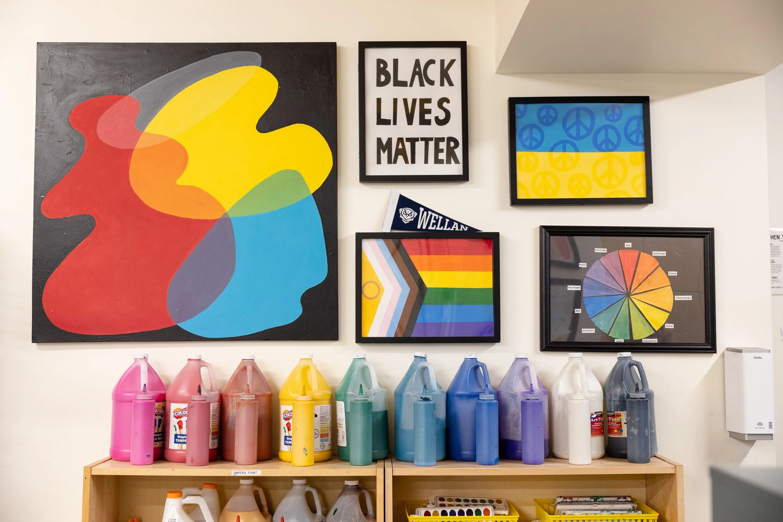 Colorful art supplies and framed pictures on a white wall at a Newton Montessori school.
