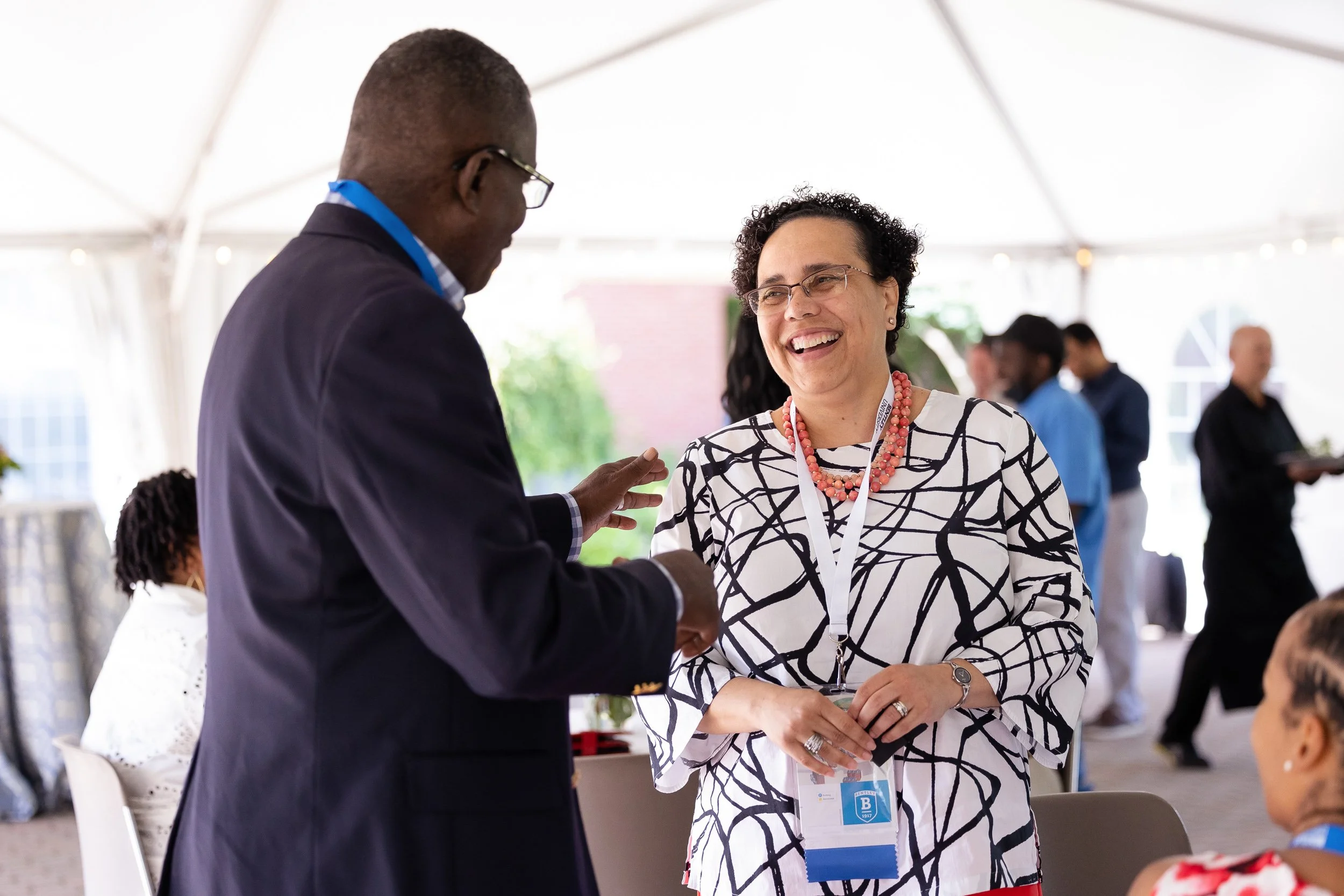 Two people talking under a tent at a social event at Bentley University in Waltham.