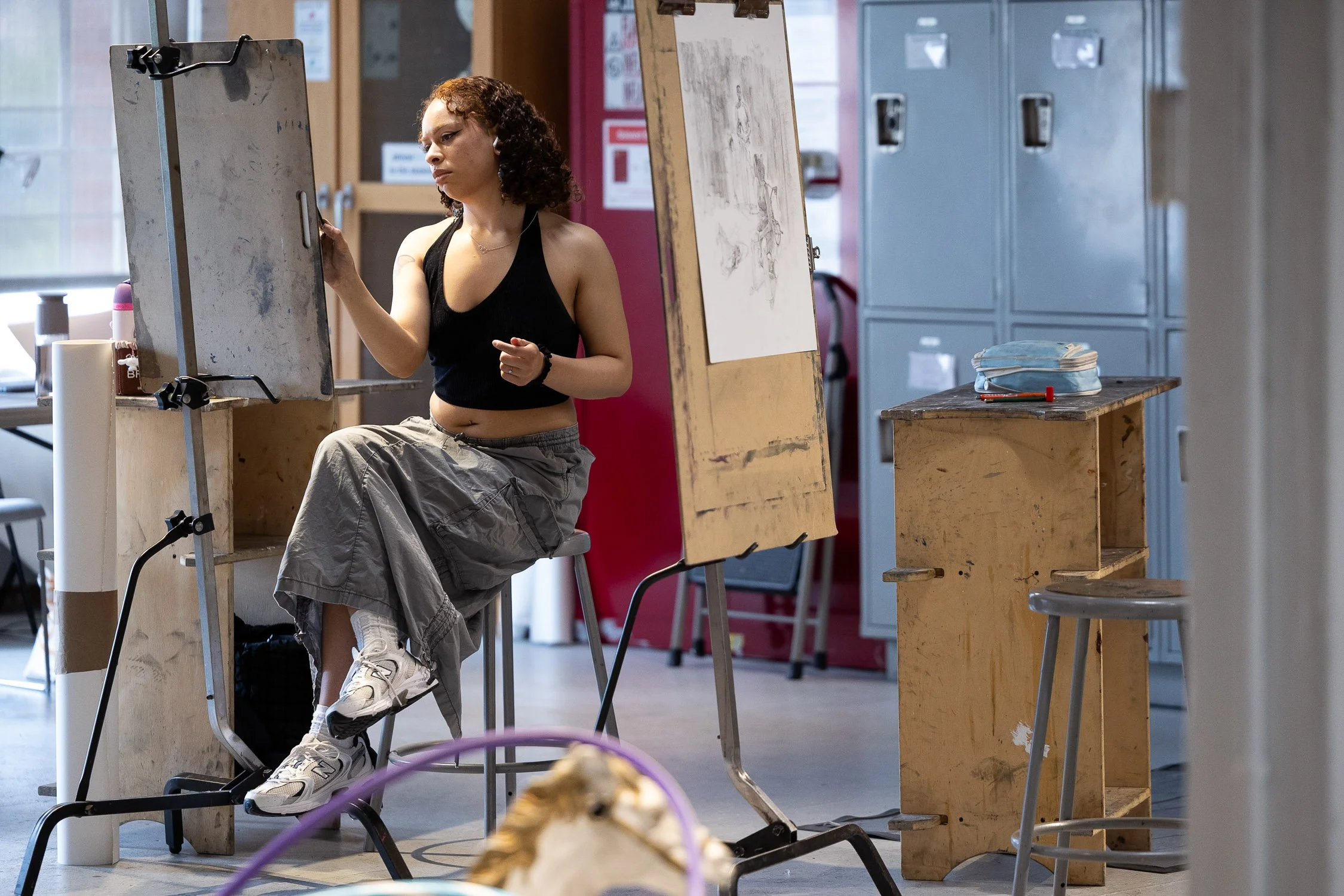 A student working at an art station in a studio environment at a Boston art school.