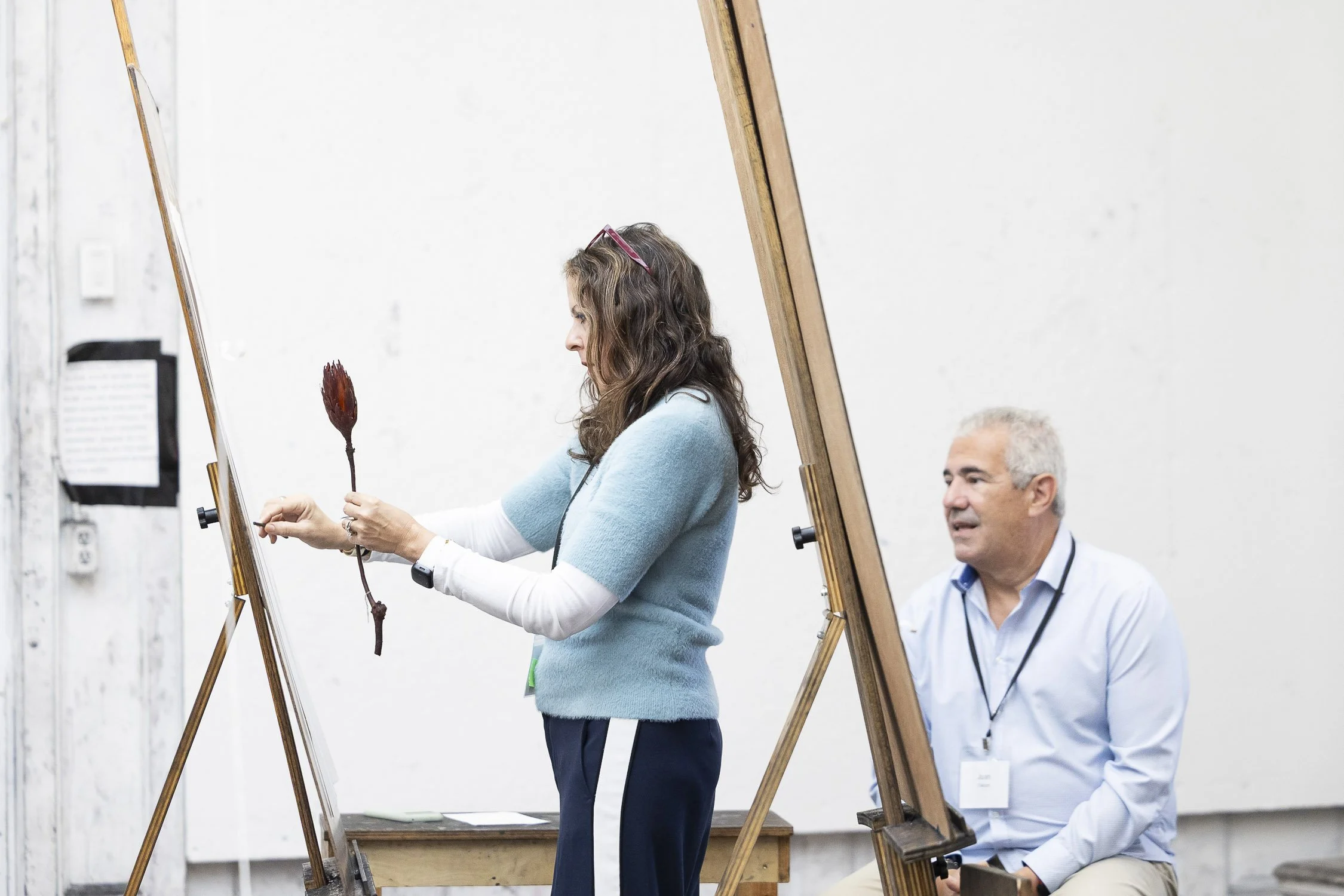 Woman holding dried flower while drawing it at easel at Rhode Island School of Design art workshop.