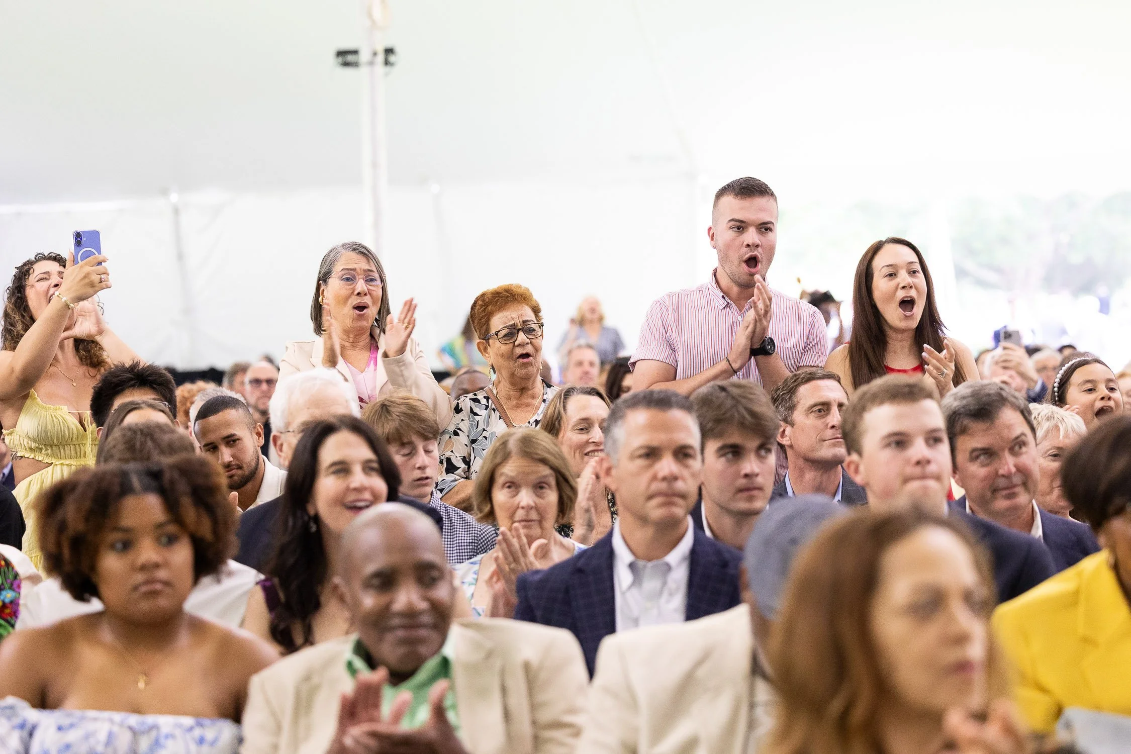 Audience memberes standing and cheering during high school graduation ceremony.