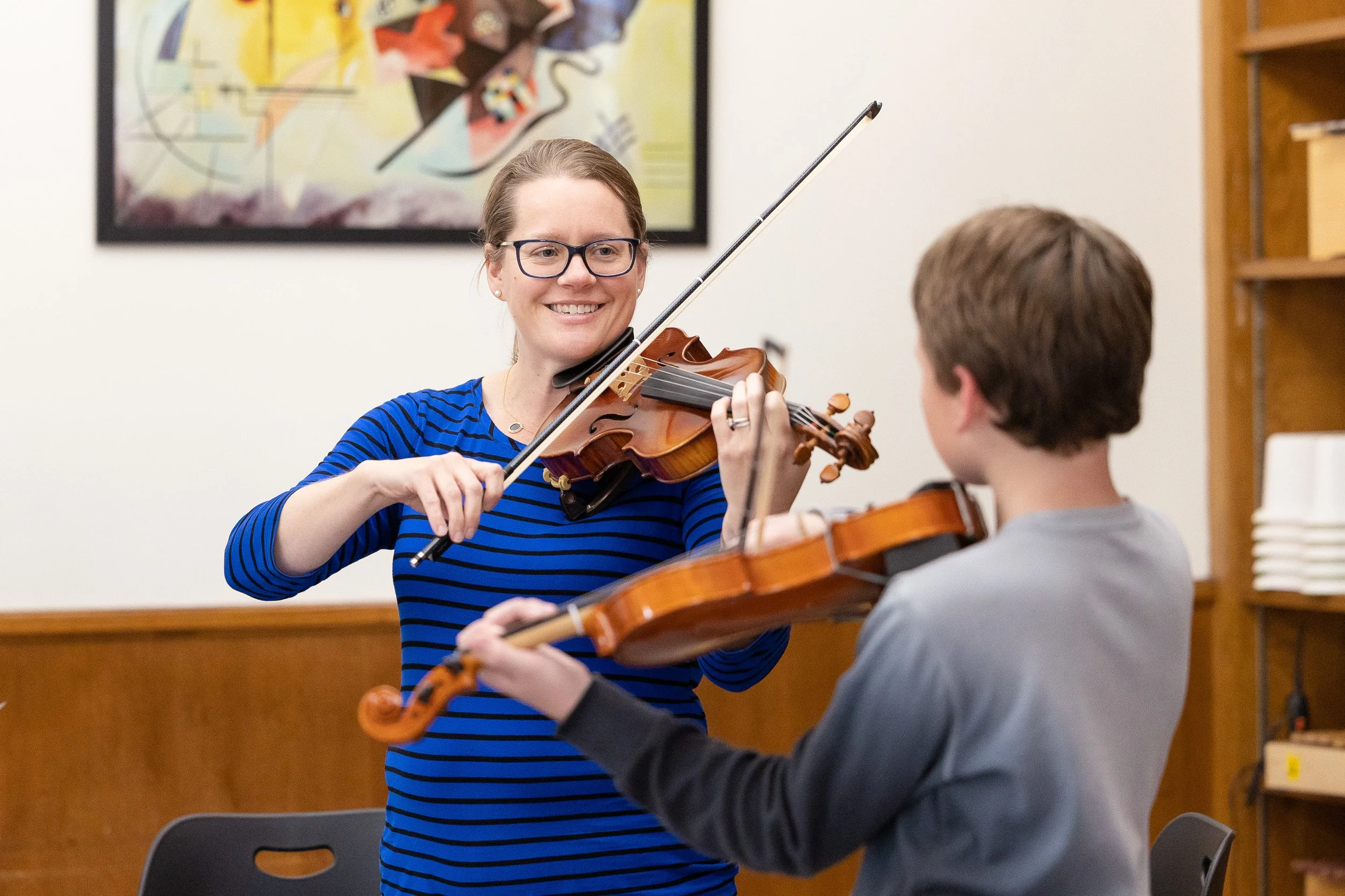 A violin teacher teaches a young boy how to play the violin in a music classroom at a Montessori school in Newton, Massachusetts..