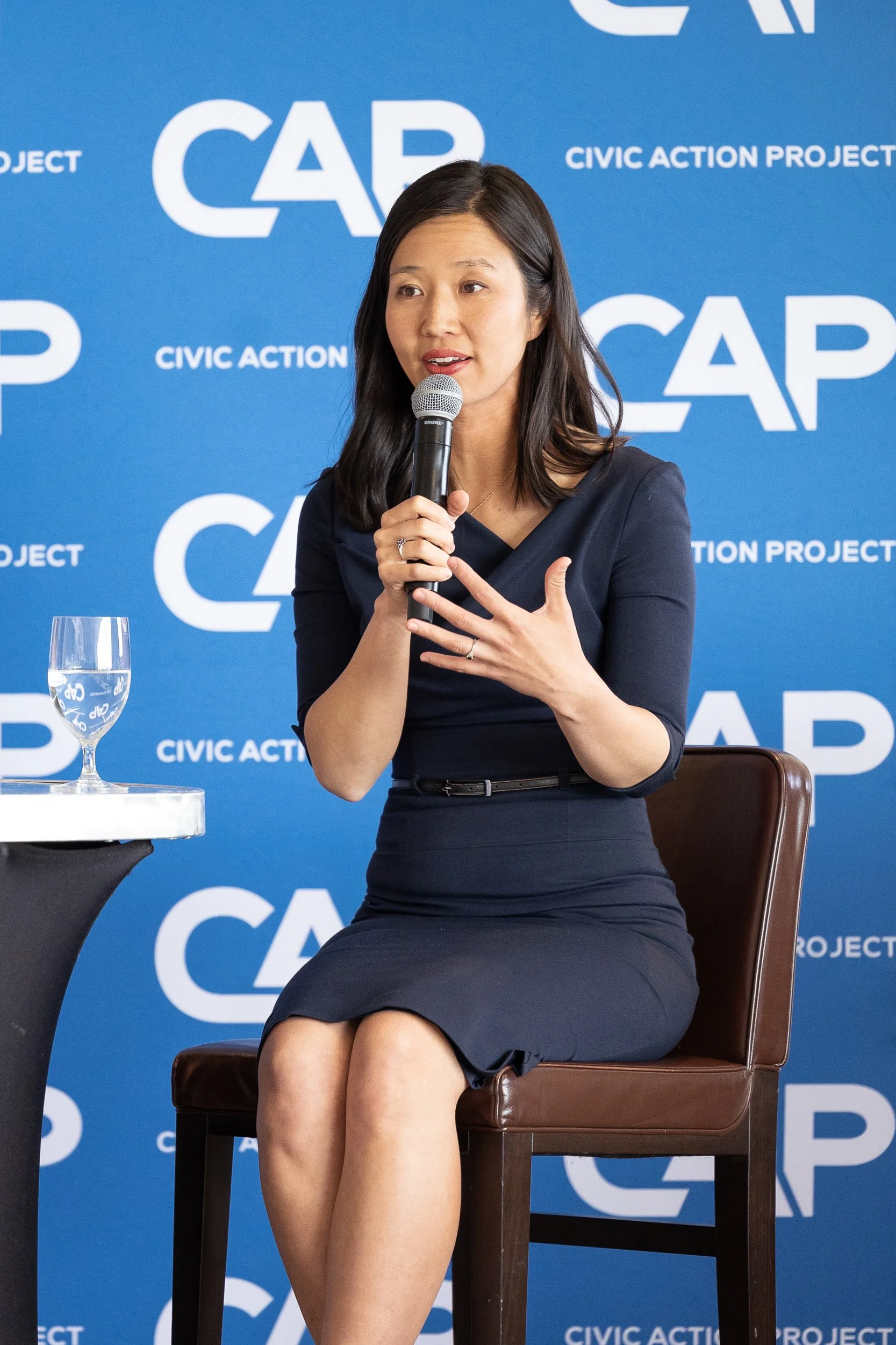 Mayor Michelle Wu speaking into a microphone in front of a Civic Action Project backdrop.