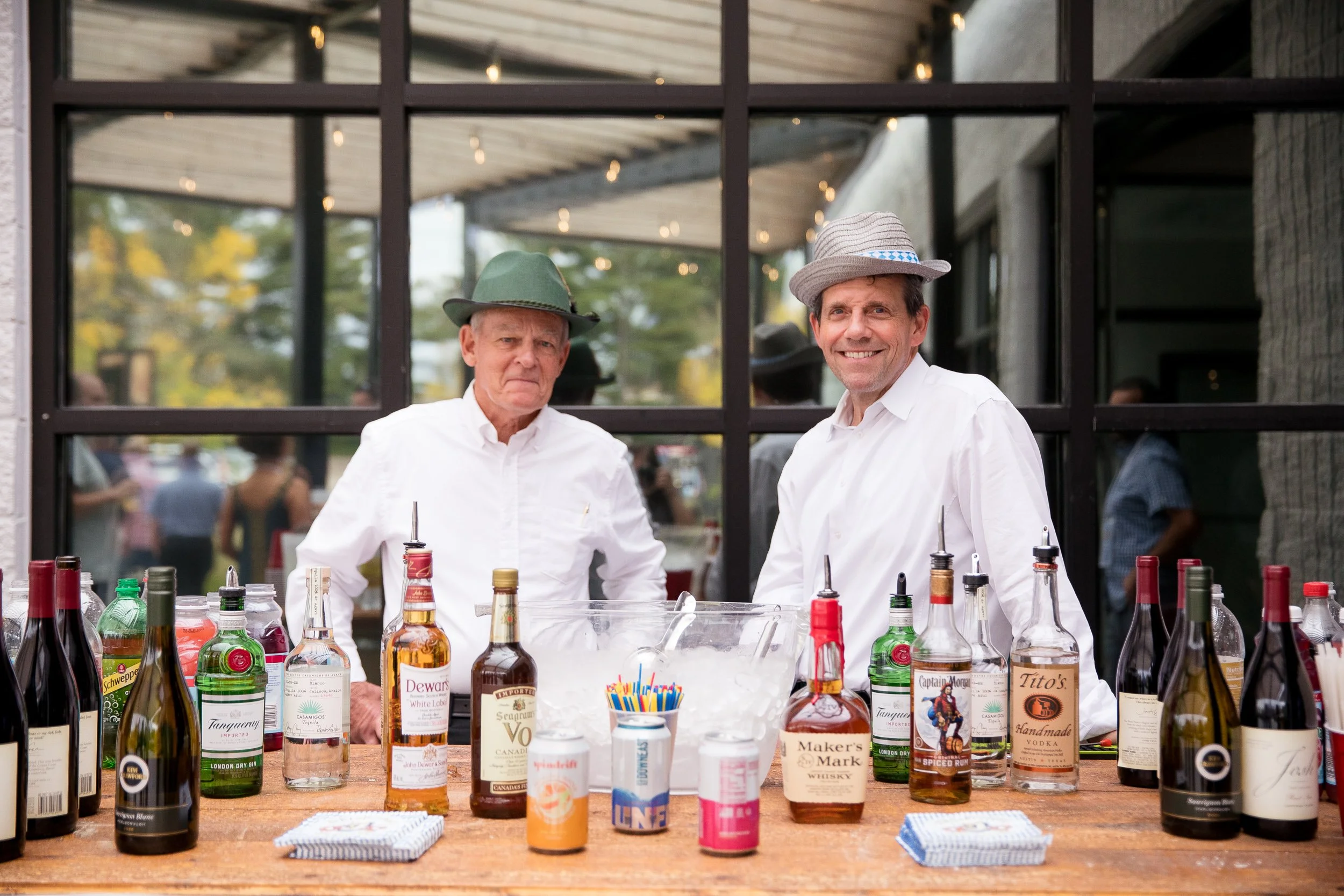 Two men standing behind a bar at an Oktoberfest event.