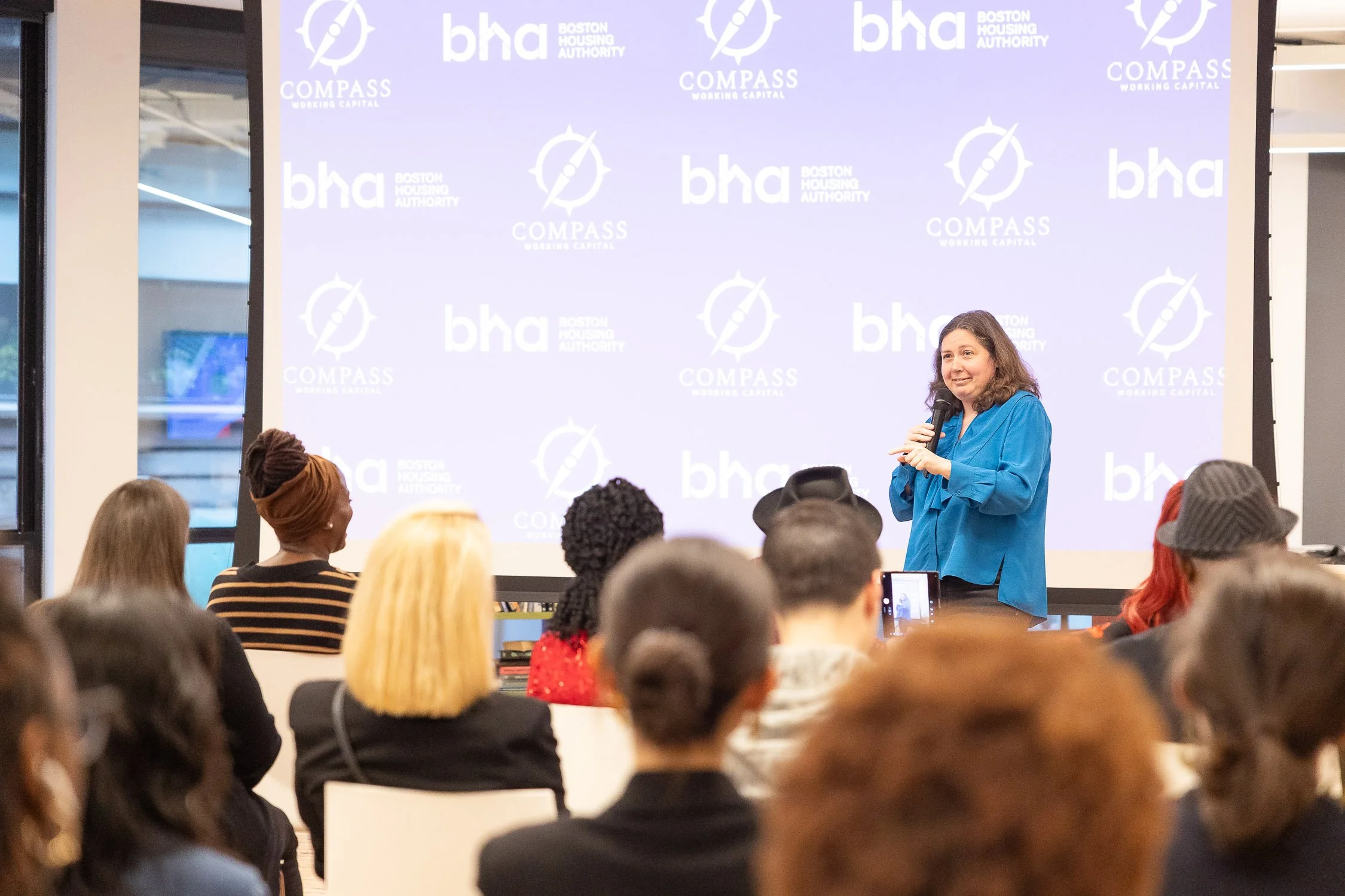 A woman in a blue shirt speaking at a presentation at an event at Sasaki Foundation building in Boston.
