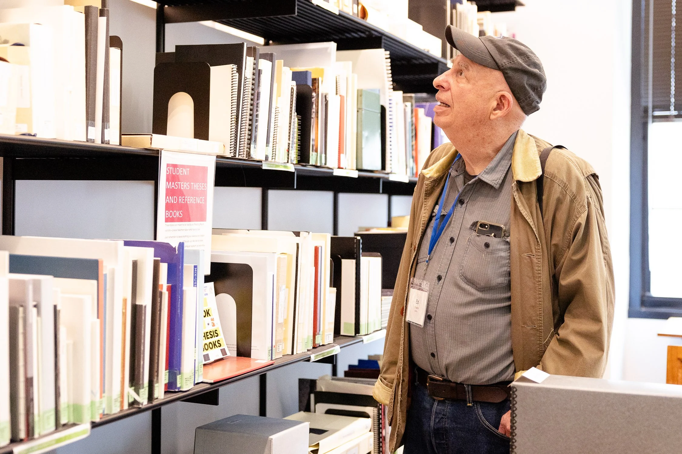 An elderly man wearing a beige jacket looking at RISD archives.