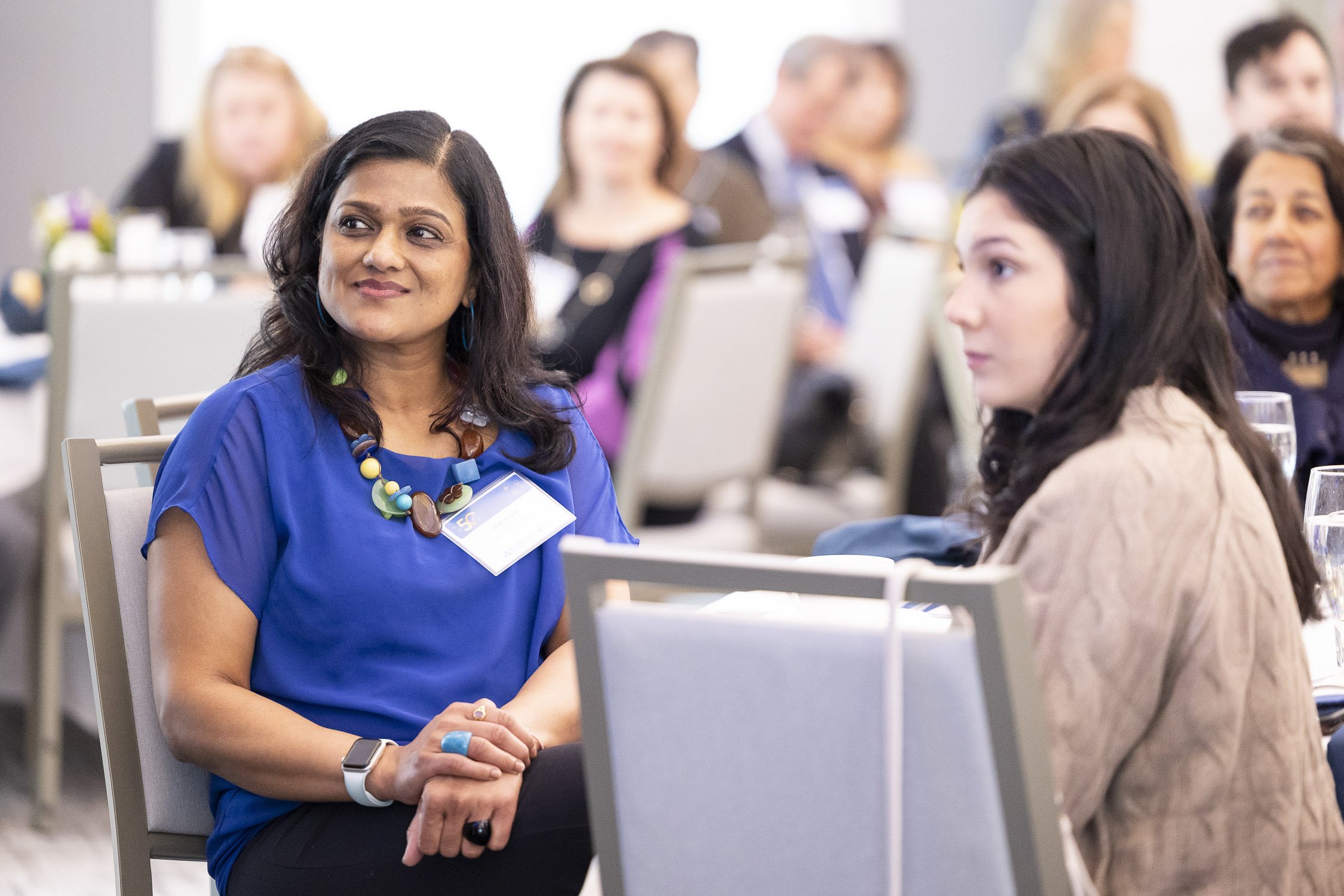 Women attending a conference, sitting at tables listening to presenter at event in Boston, Massachusetts.