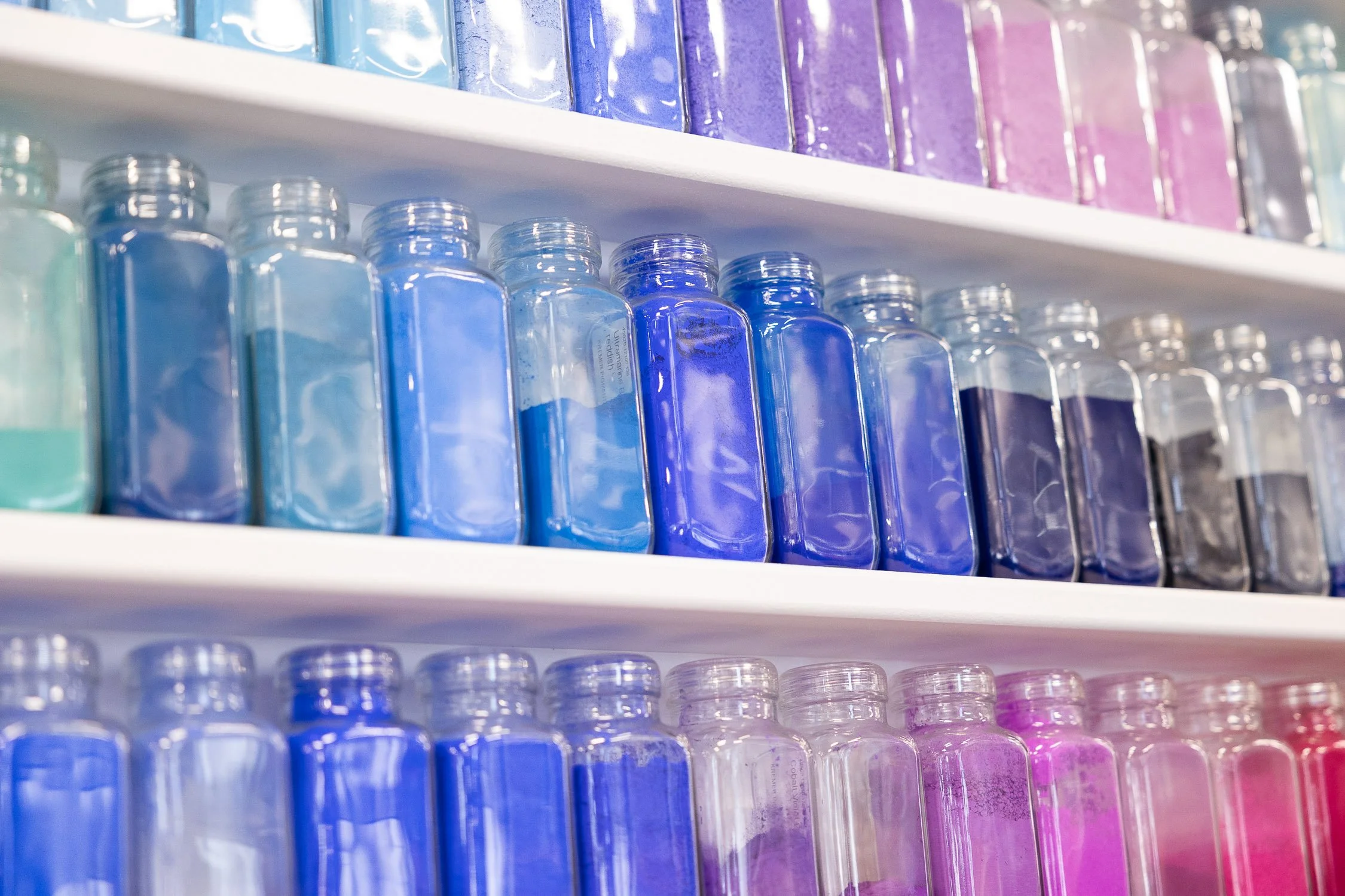 Shelves of colorful ink bottles arranged in a gradient from green to purple at Rhode Island School of Design.
