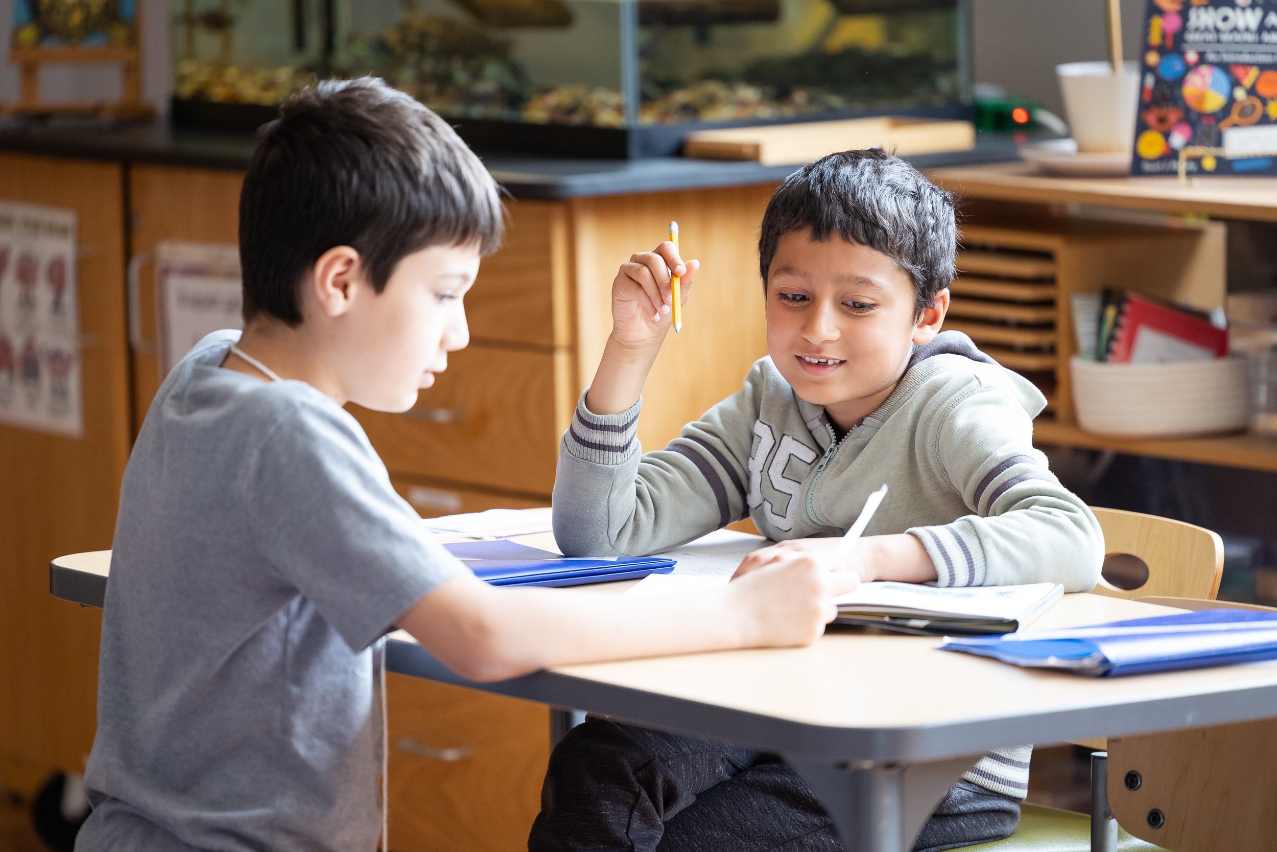 Two elementary students are sitting at a table in a classroom at a private elementary school in Boston.