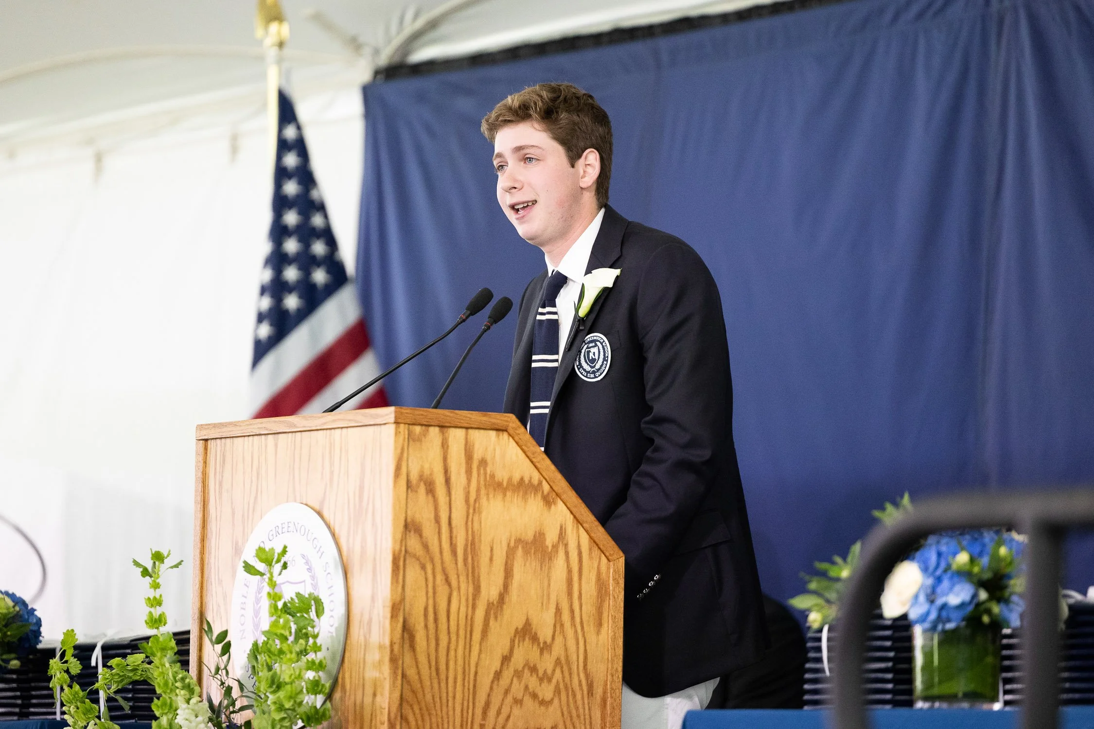 A young man giving a speech at a podium during Boston independent school graduation.