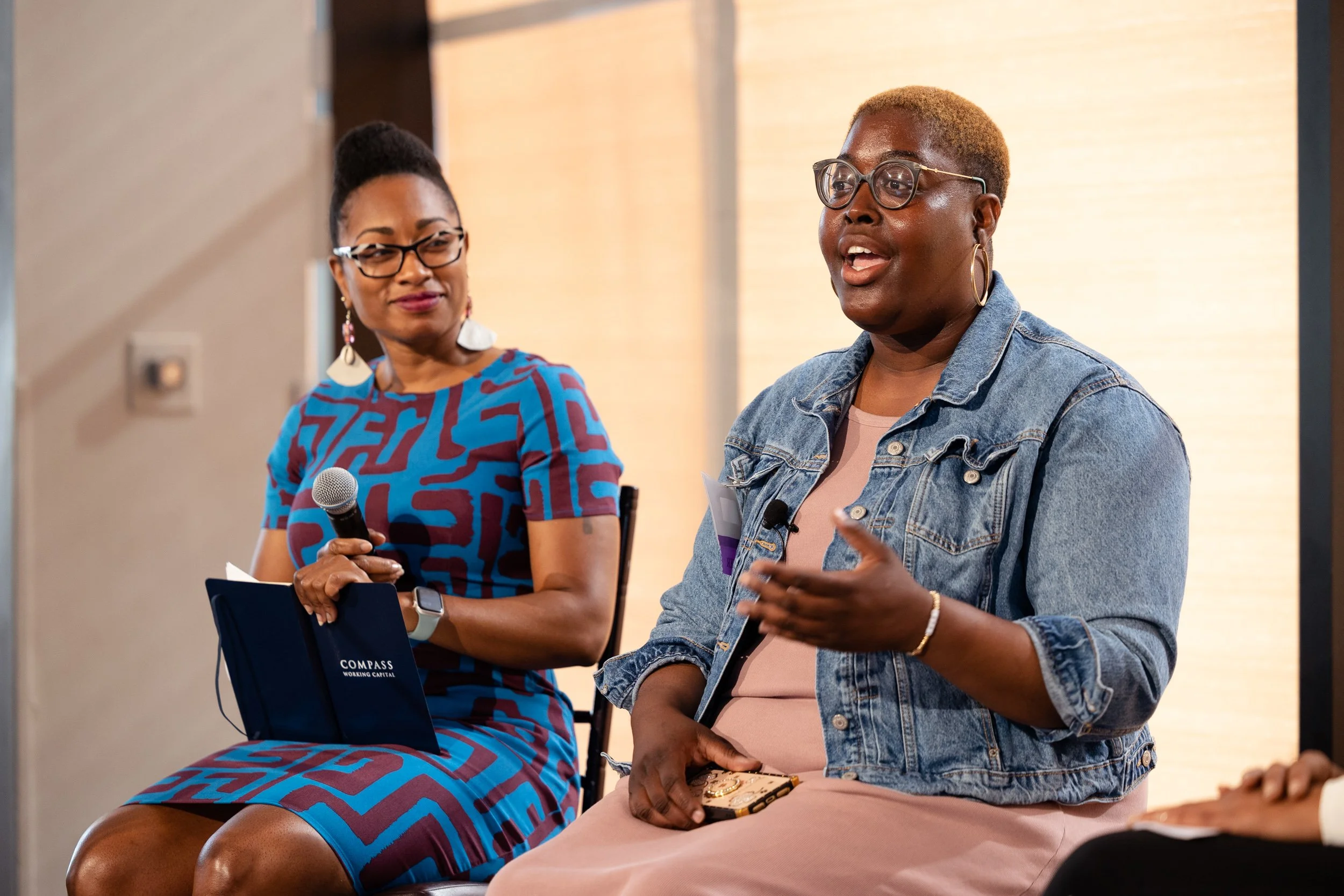 Two women sitting on stage, engaged in discussion at Compass Woring Capital event in Boston.