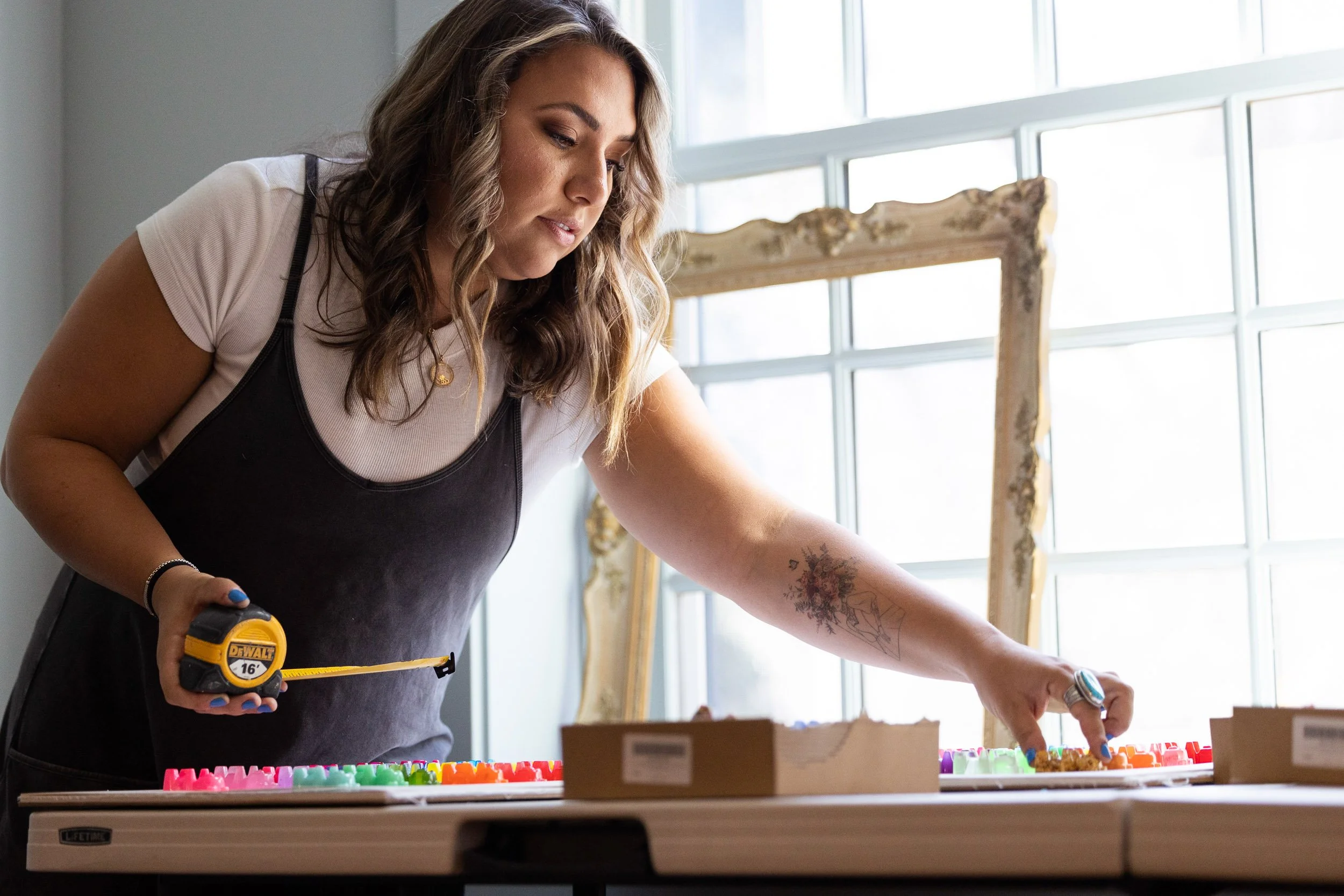 A female artist working on a colorful resin craft project at a table in her home in Newton, Massachusetts.