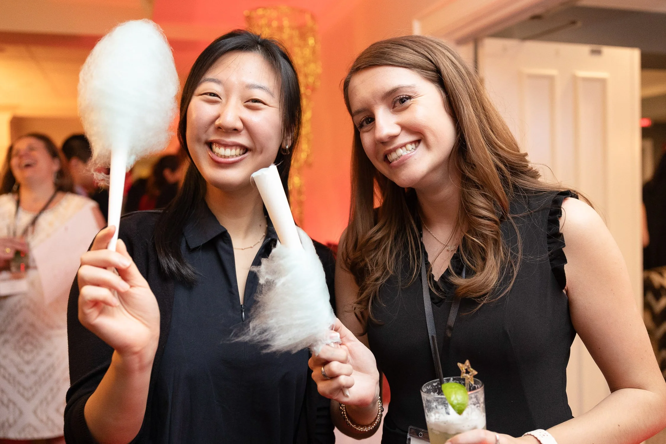 Two women smiling and holding cotton candy at a fundraising event in Newton, Massachusetts.