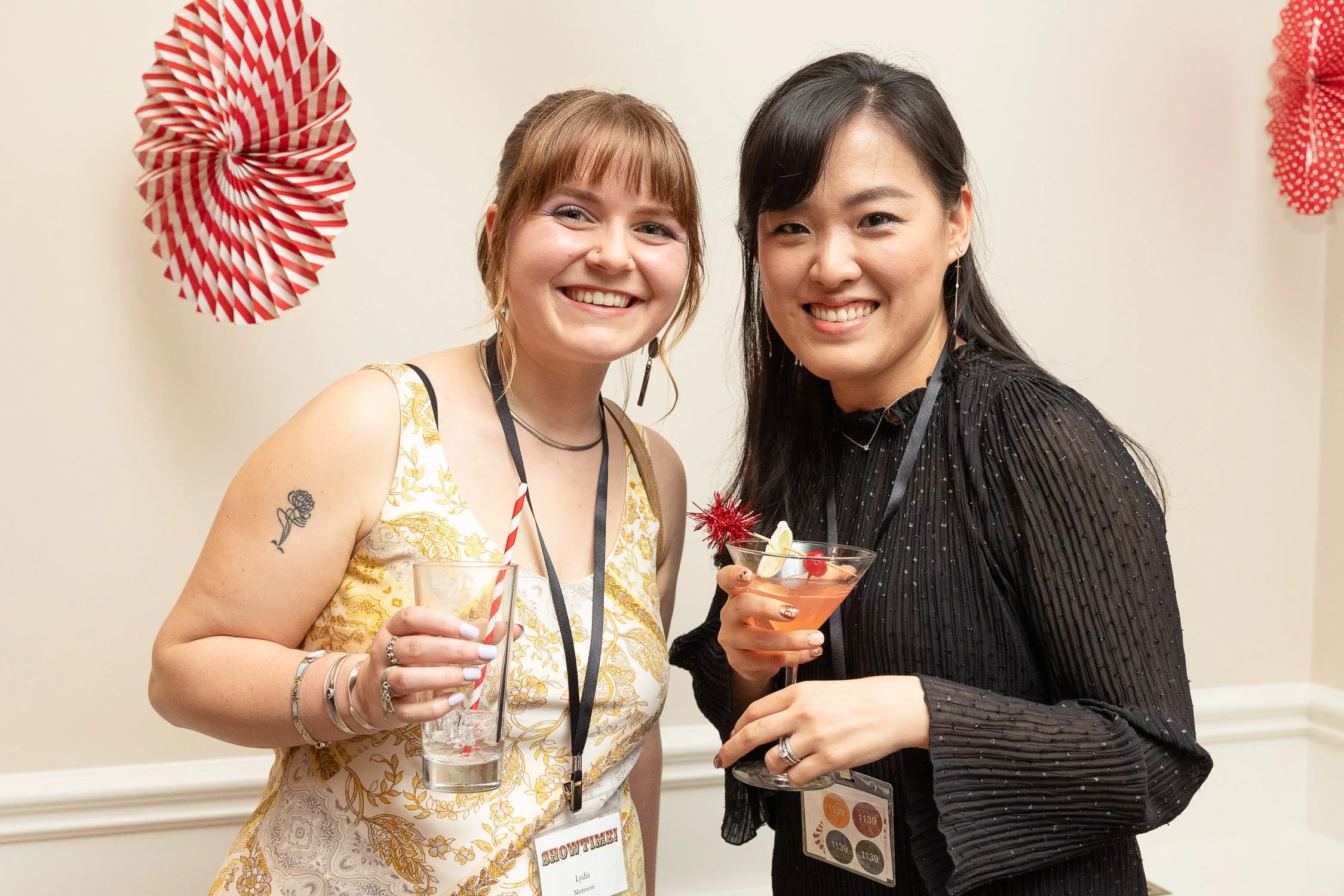 Two women smiling at a party, holding drinks, at Wellan Montessori annual gala.