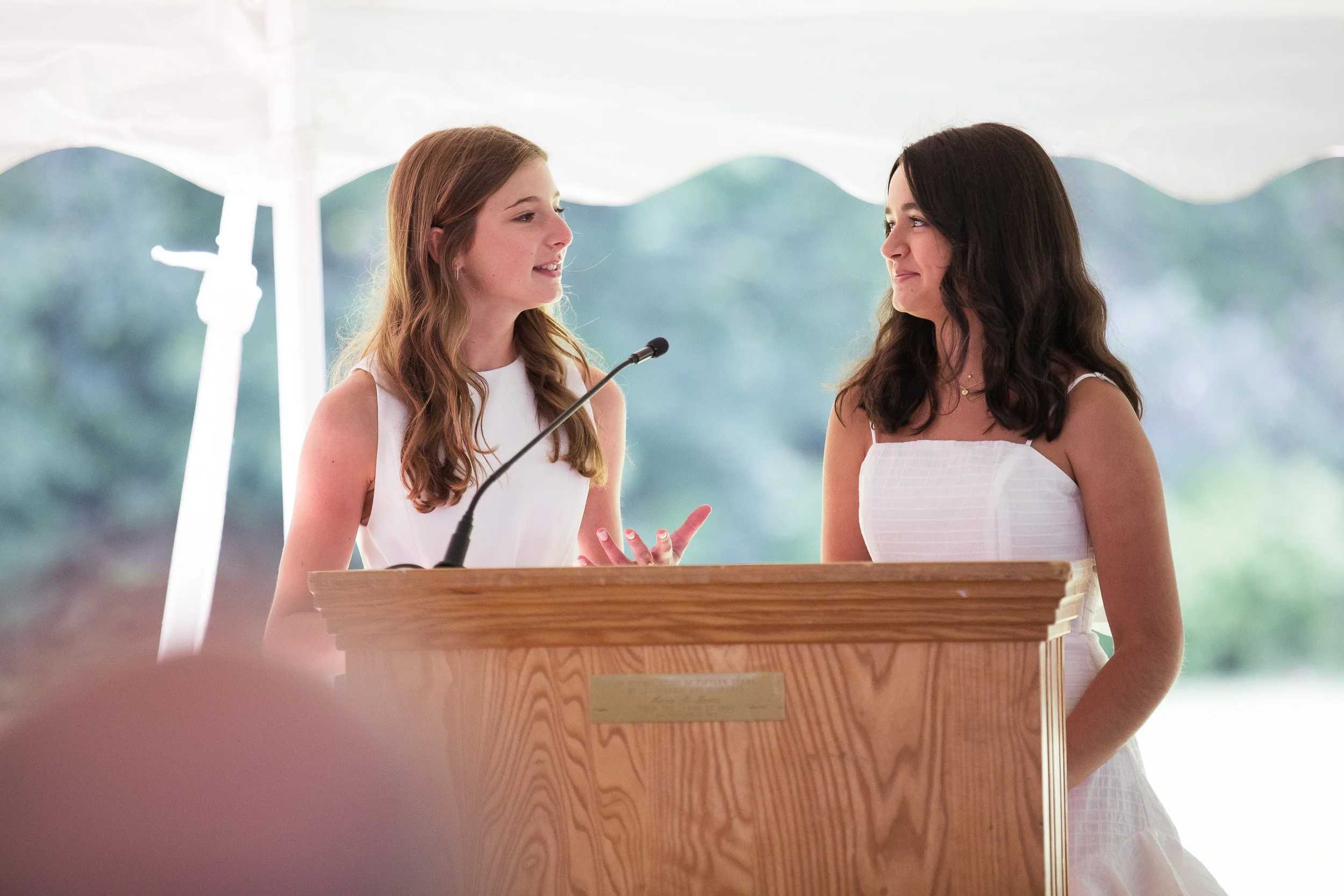 Two middle school students standing behind a wooden podium during a speech at graduation.