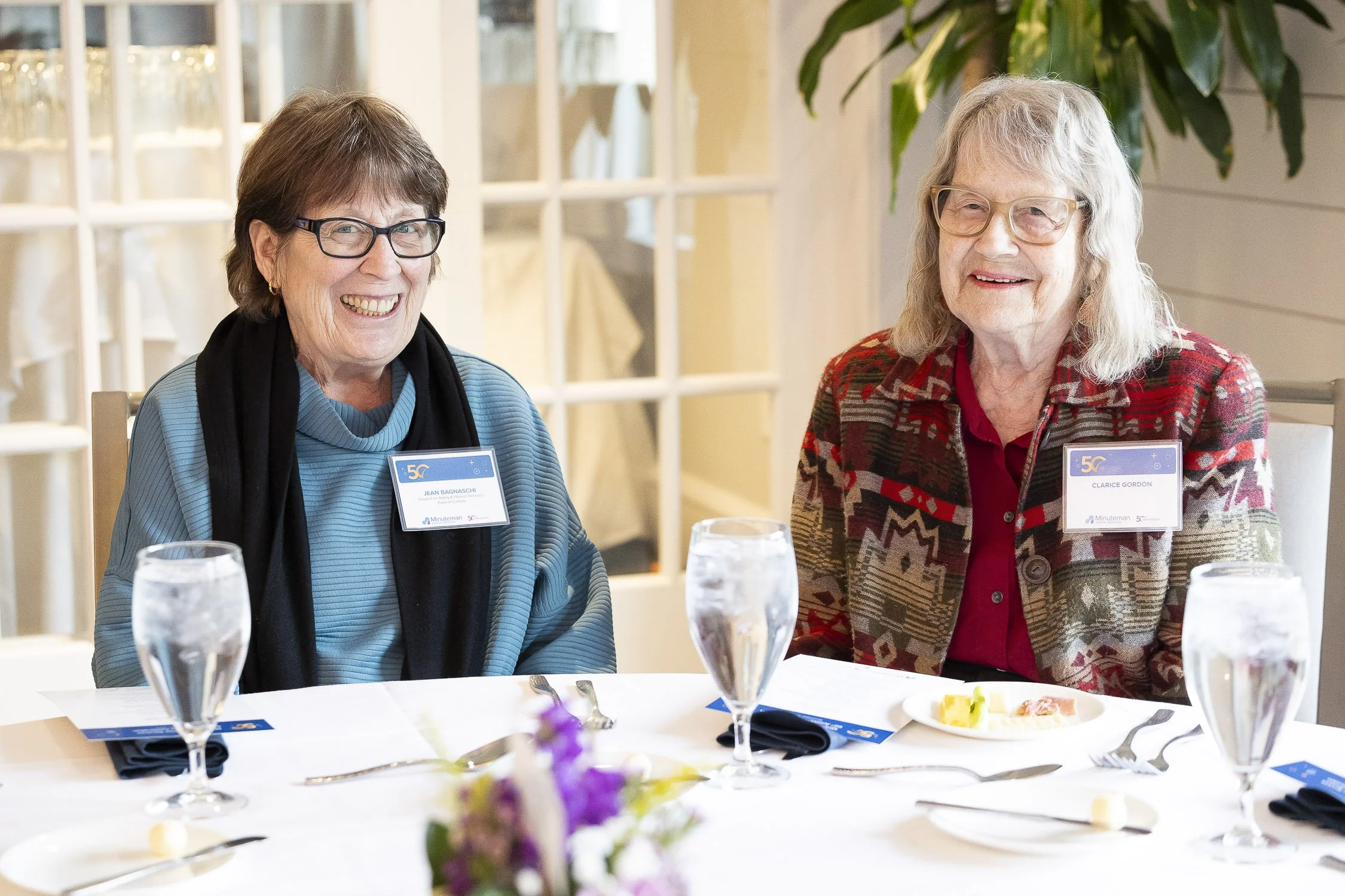 Two women sitting at a dining table at a nonprofit event in Boston, Massachusetts.