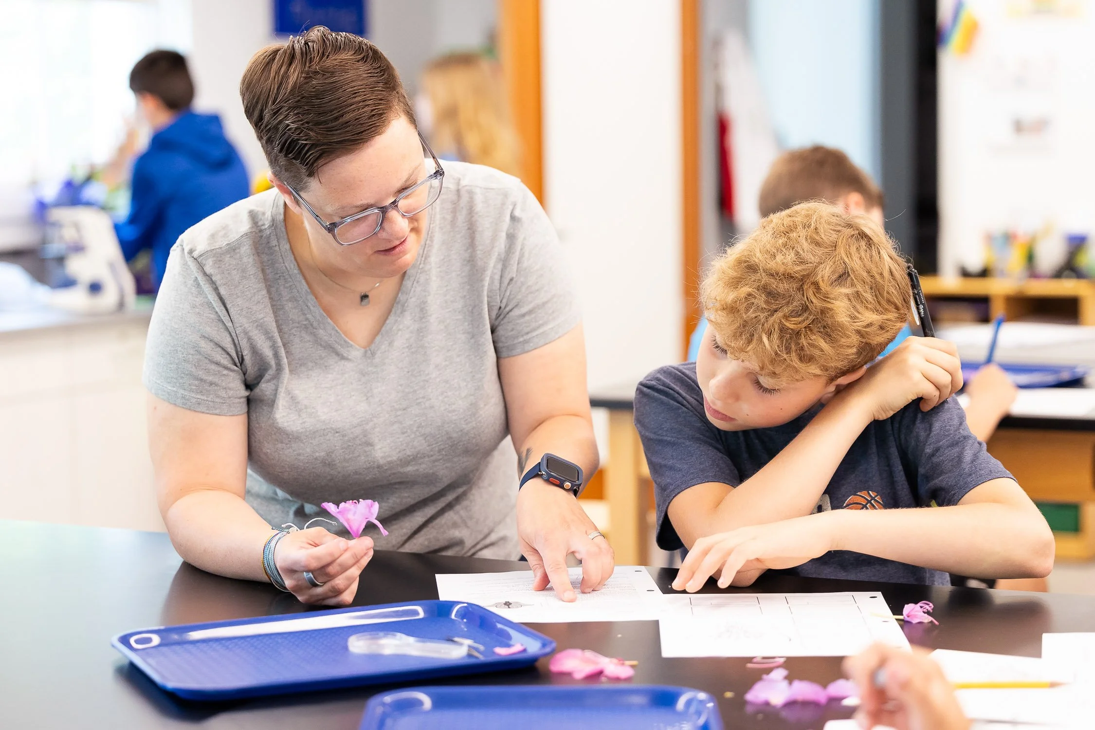 Teacher assisting a student with classwork at a school desk in a classroom at an independent middle school in Massachusetts.