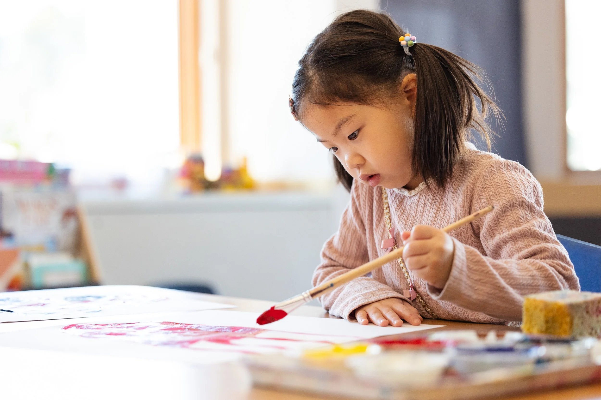 Young girl painting with a brush at in art class.