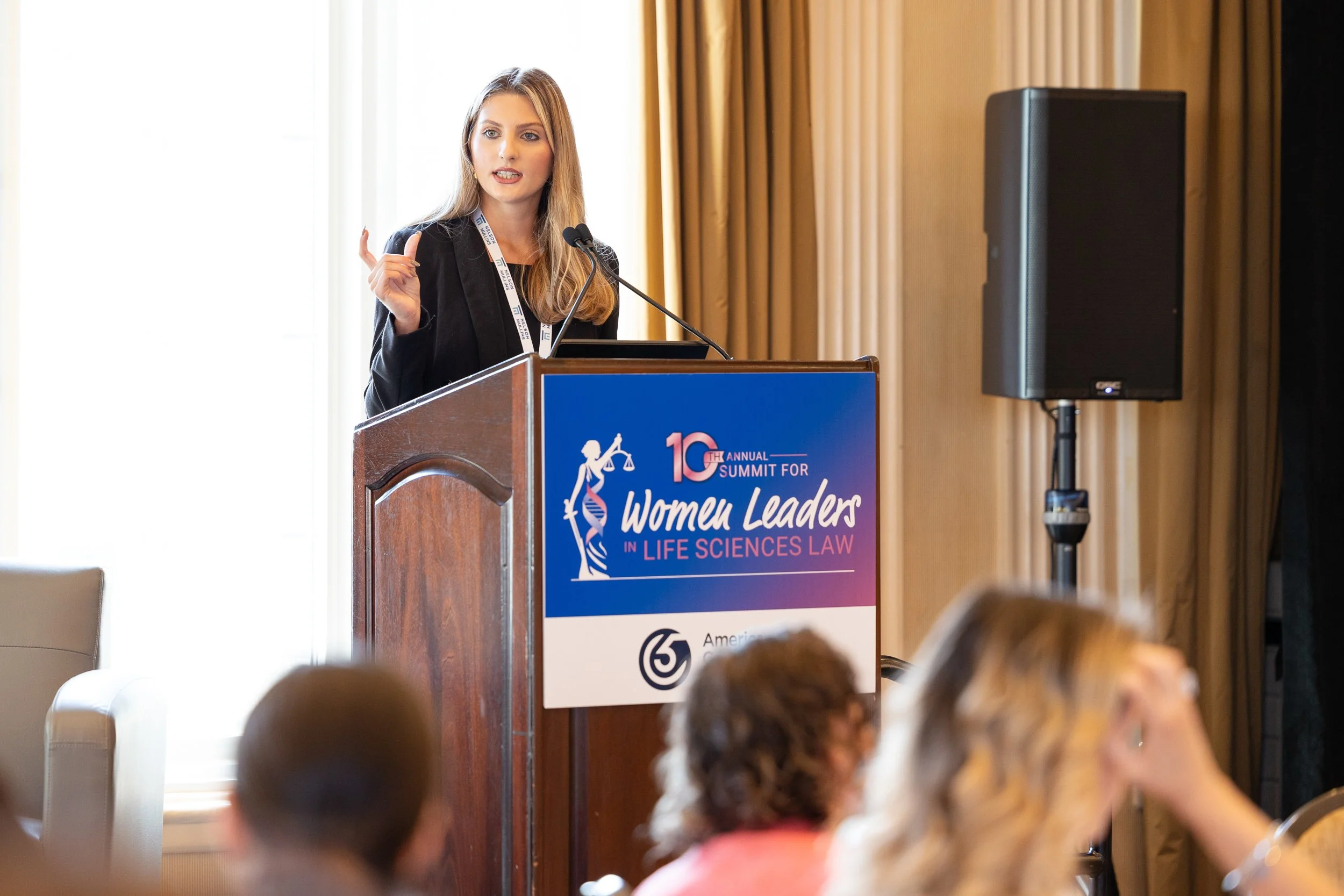 A woman speaking at a podium during the 10th Annual Summit for Women Leaders in Life Sciences Law in Boston.