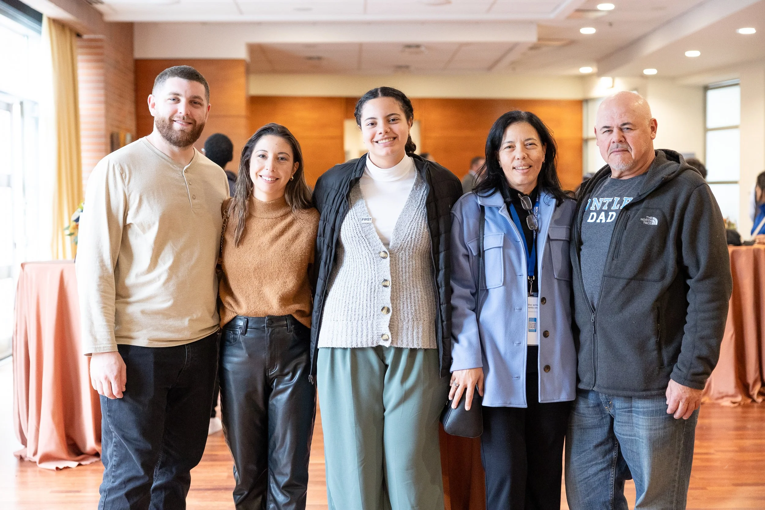 Group of people standing together indoors, smiling at a Bentley University networking event.