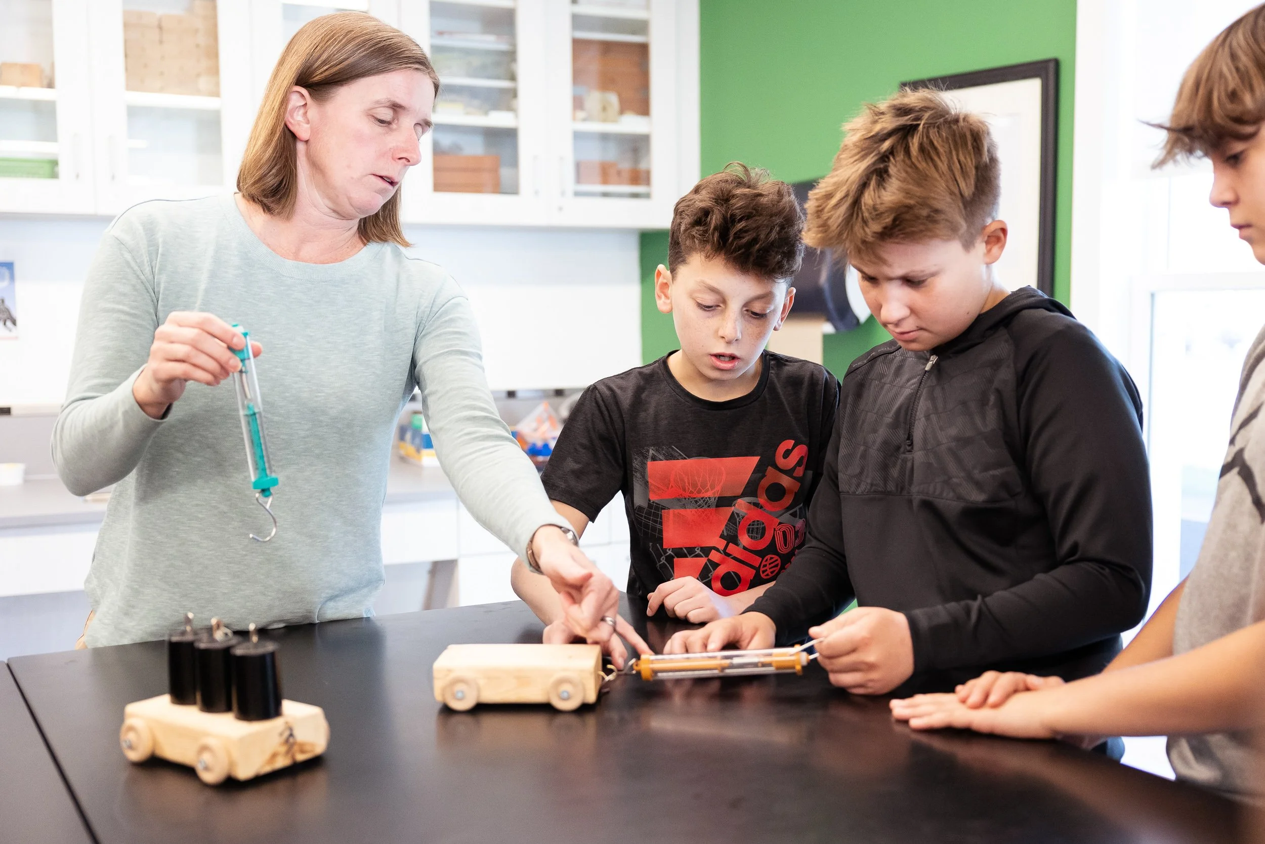 A science teacher demonstrates an experiment to three middle school students at an independent middle school in Boston.