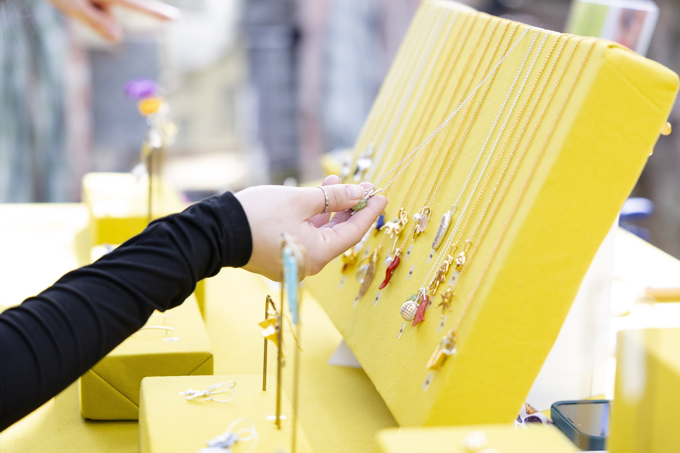 A person shopping for necklaces outdoor market stall at RISD Craft in Providence, Rhode Island.