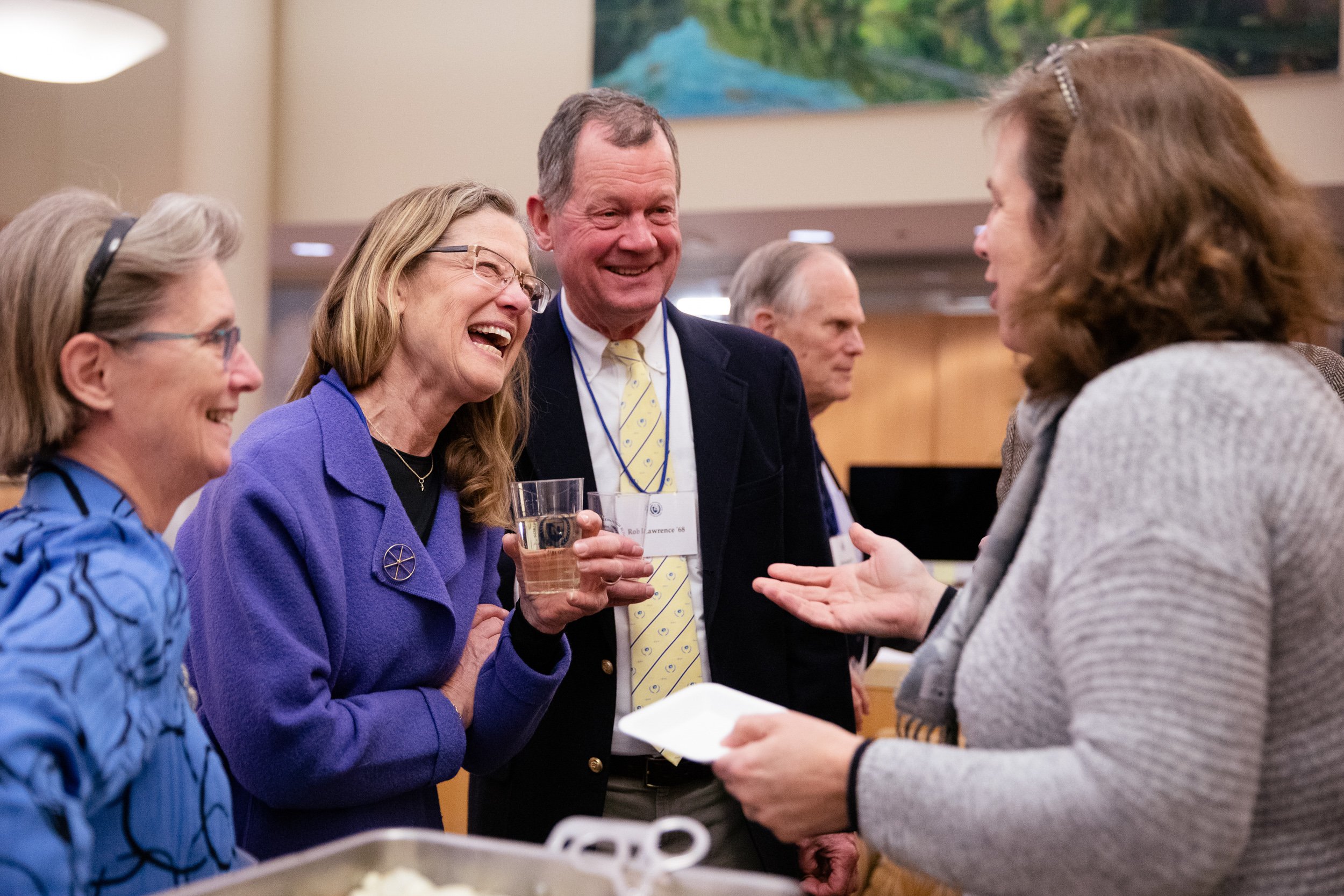 Group of people at a social gathering, engaged in conversation and smiling. 