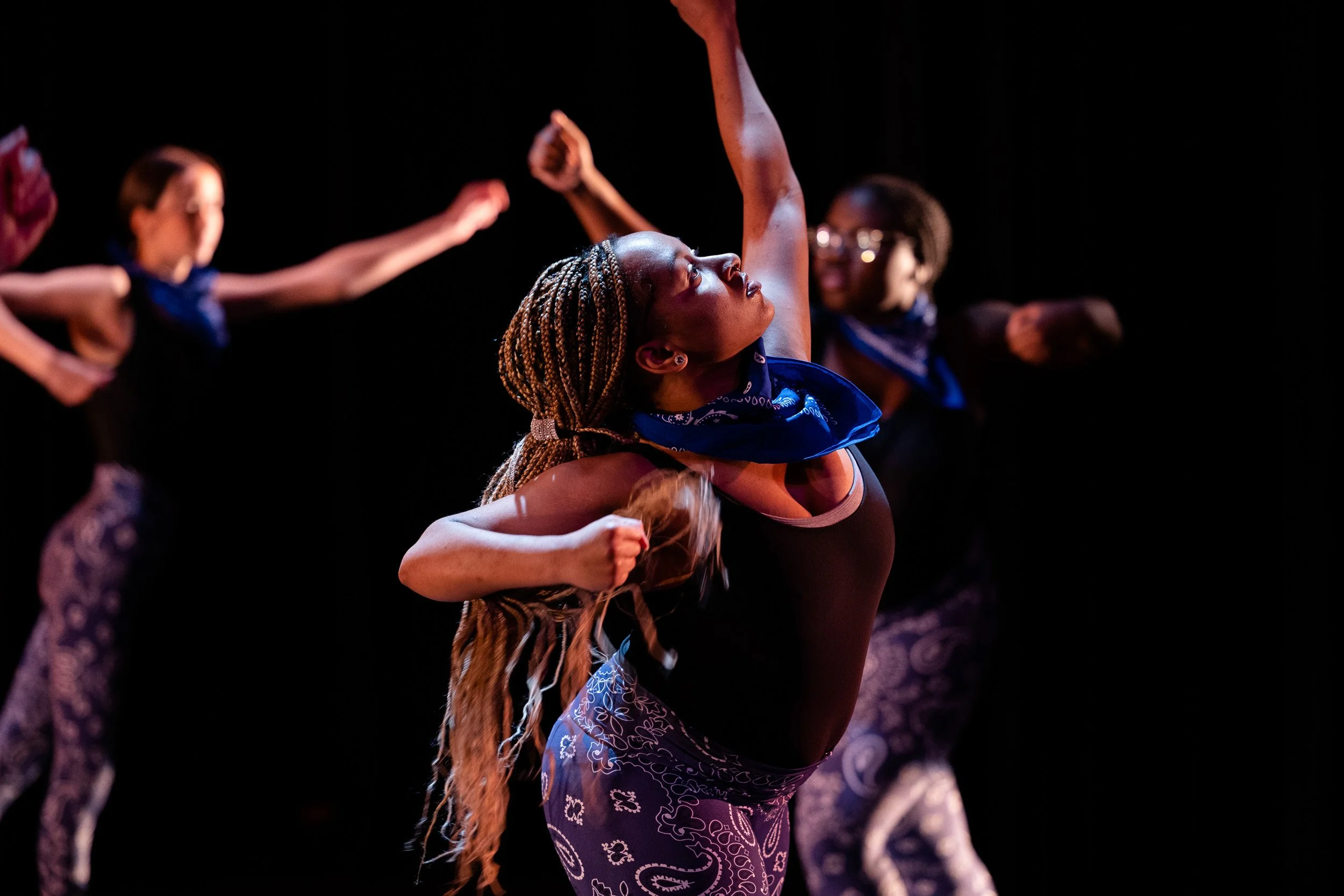 Dancer performing on stage with other dancers in background in a Massachusetts high school dance concert.