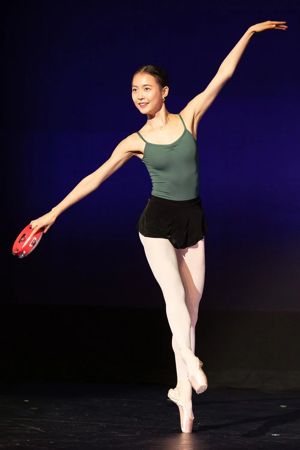 Ballet dancer on stage holding a tambourine in an independent school dance performance.