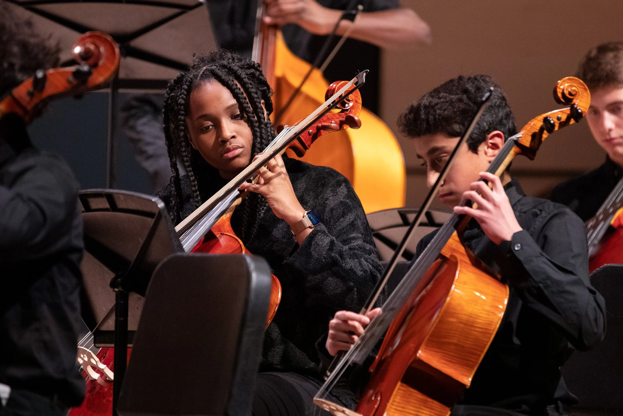 Two young musicians playing violins during a concert.