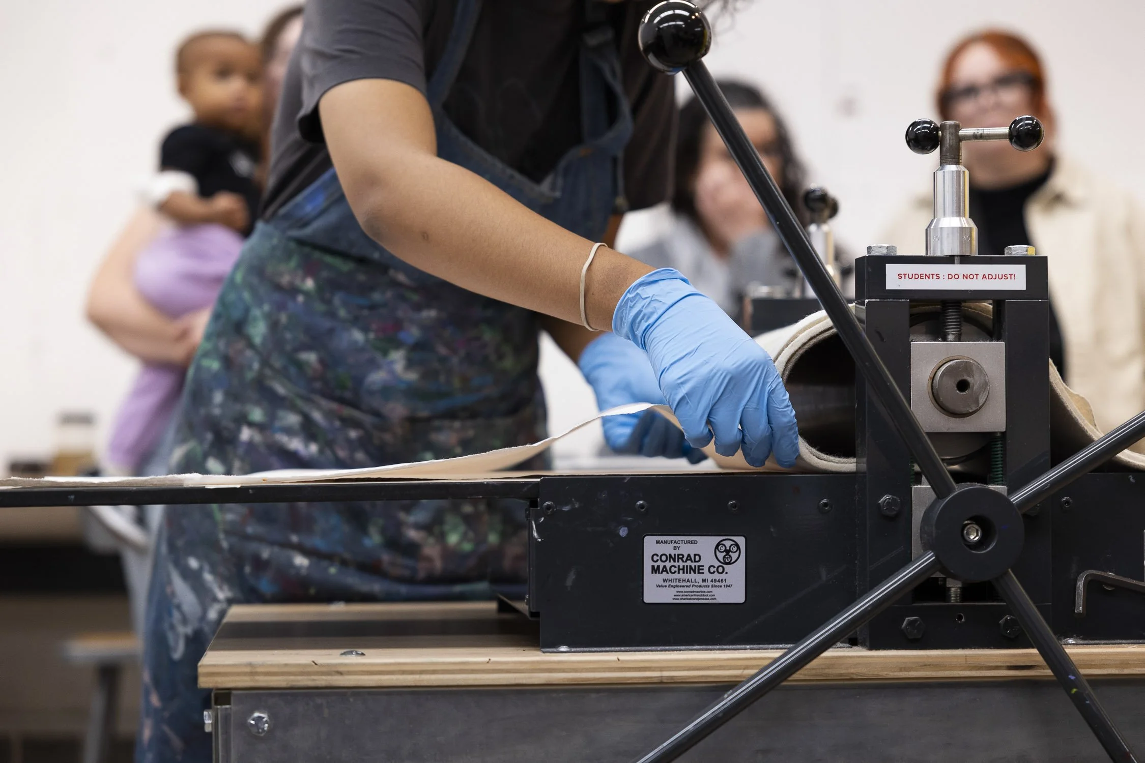 Person demonstrating printing press in an art school workshop.